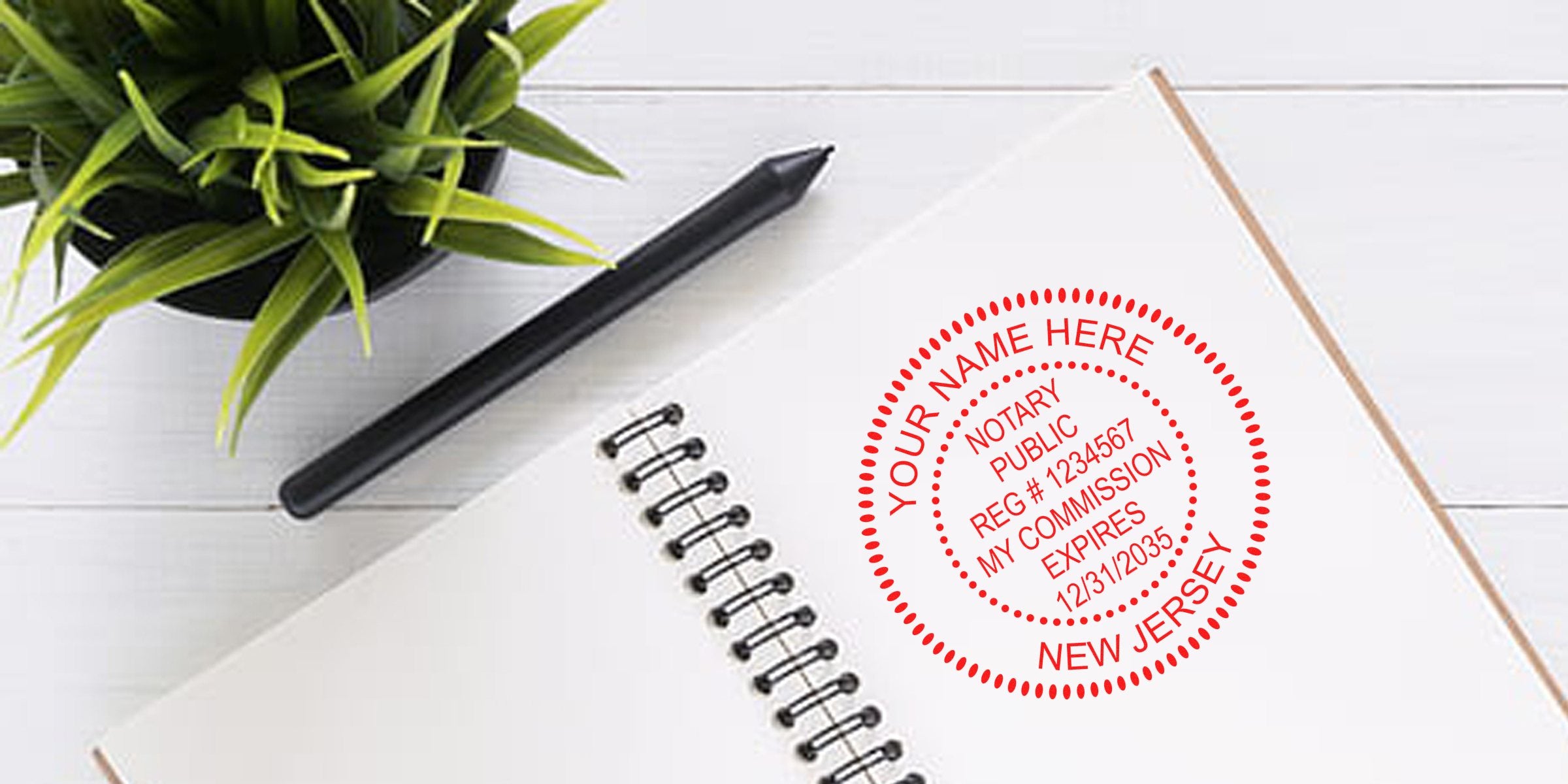 Red circular New Jersey notary stamp mockup on open spiral notebook with black pen and green potted plant on white wood desk — customizable name, registration number and commission expiration date
