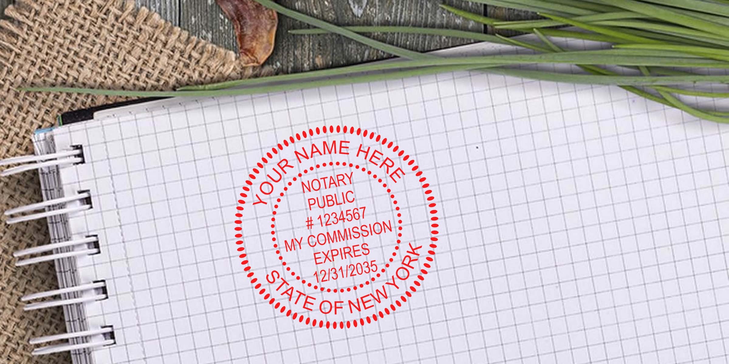 Spiral graph-paper notebook on burlap with green grass; red circular notary public stamp reading "Your Name Here, Notary Public #1234567, My Commission Expires 12/31/2035, State of New York."