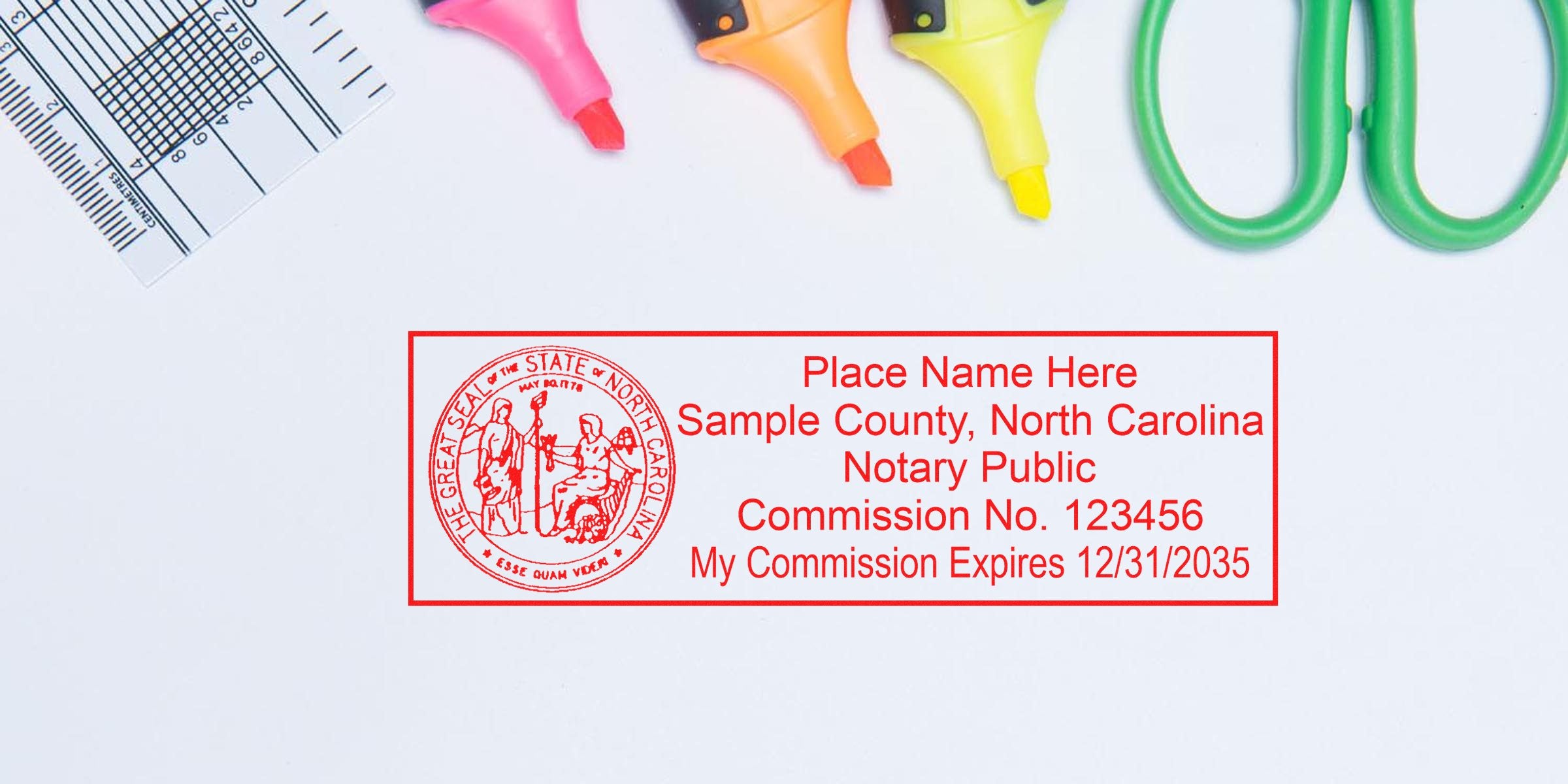 Red rectangular North Carolina notary public stamp mockup with state seal, sample county, commission number and expiration date, placed on white desk beside green scissors, neon highlighters and a ruler.