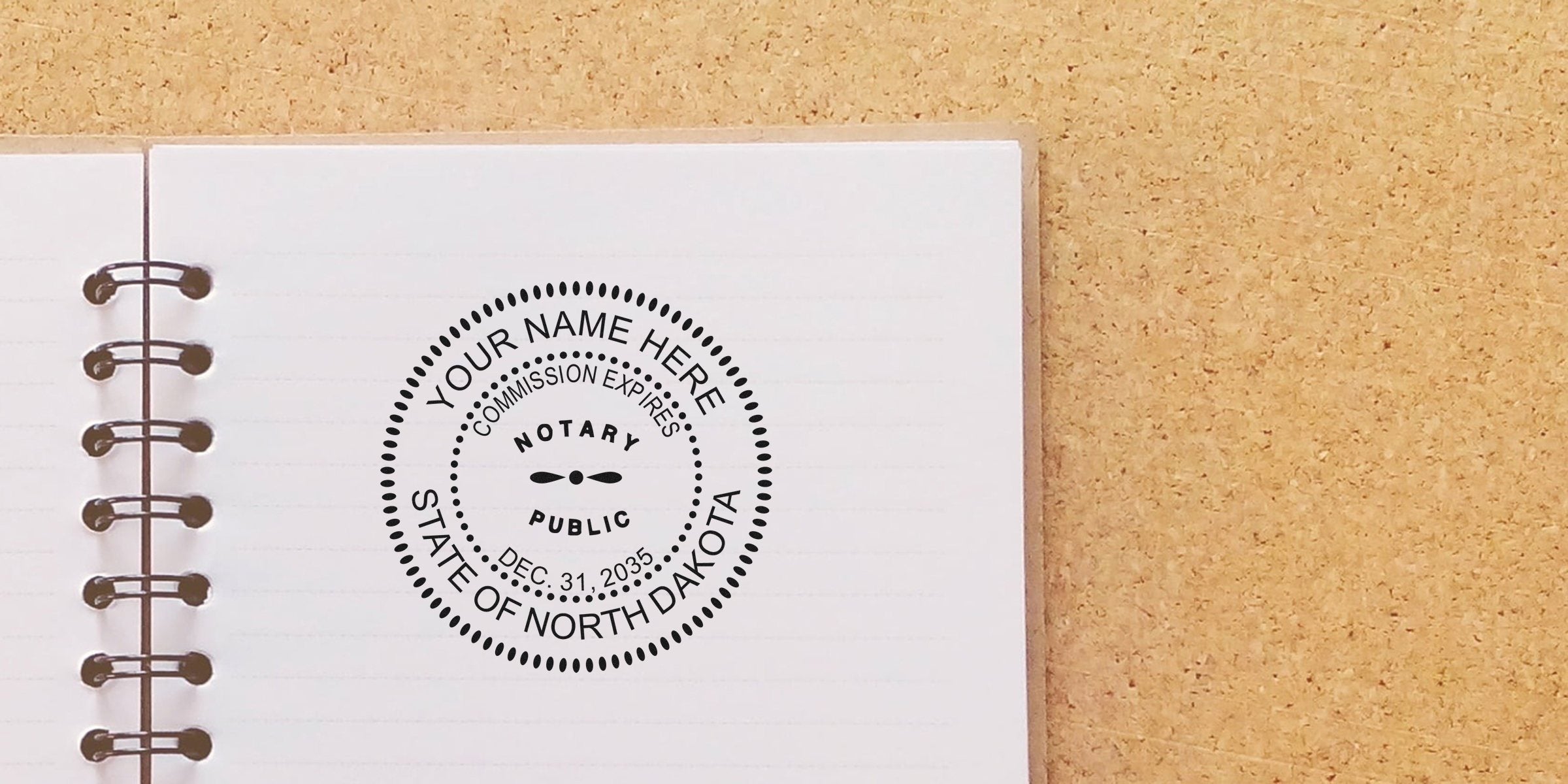 Spiral notebook open on a corkboard with a circular black notary public stamp reading "State of North Dakota" and placeholder "Your Name Here," commission expires Dec 31, 2035