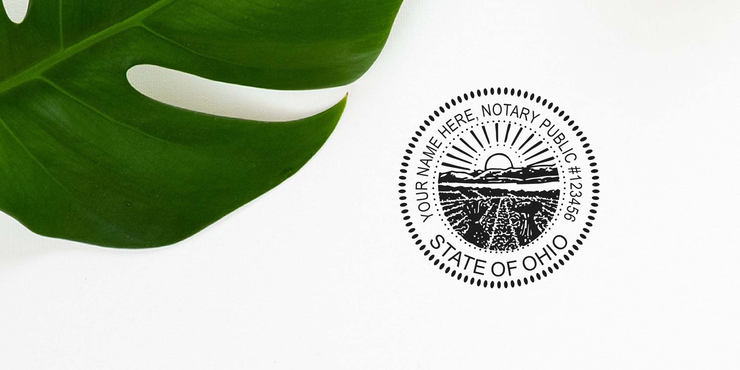 Ohio notary public round seal stamp showing sunrise over farm fields on a white background, placed next to a large green monstera leaf
