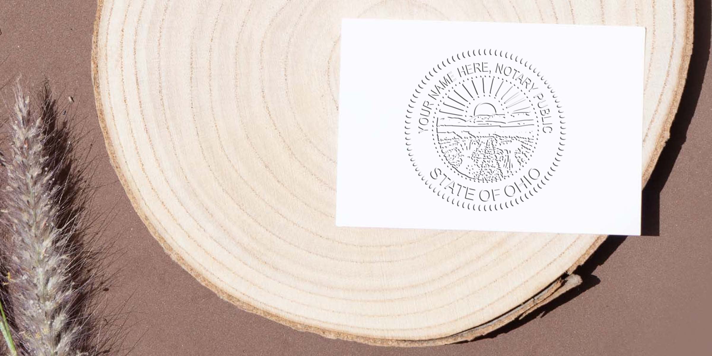 White card showing a circular "State of Ohio" notary public seal placed on a round wood slice over a brown background with dried grass accents