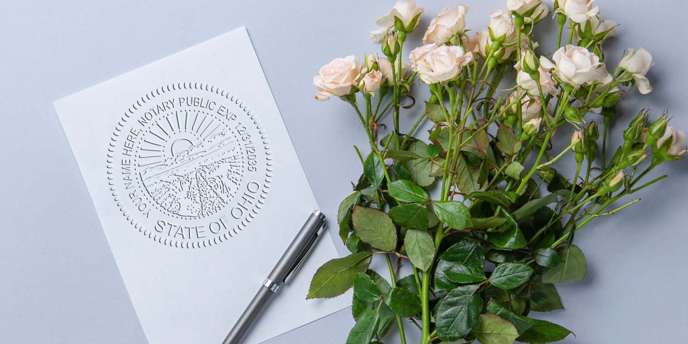 Embossed State of Ohio notary seal on white paper with silver pen and pale pink roses on gray background, floral stationery and legal document concept