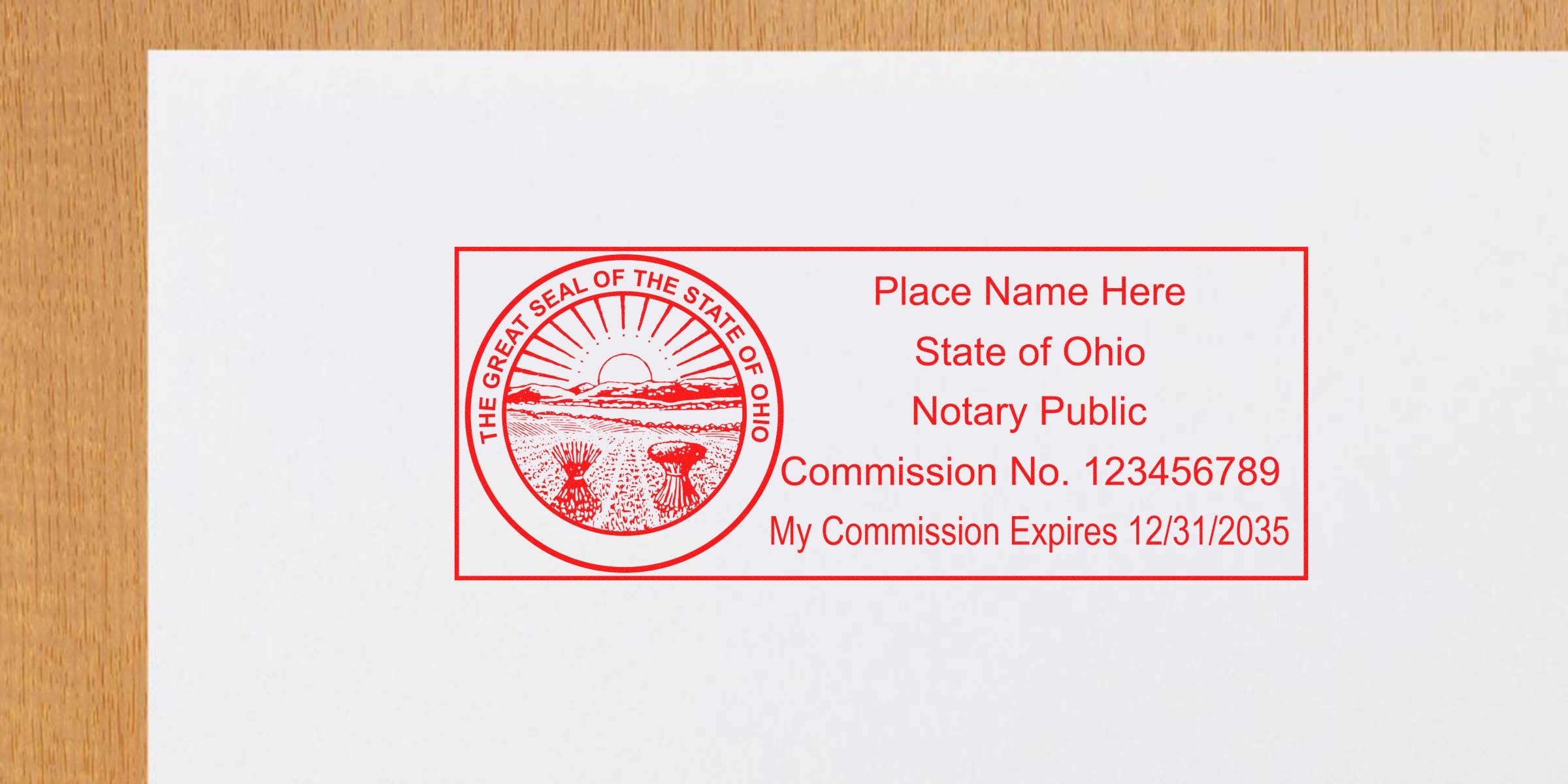 Red rectangular Ohio notary stamp on white paper featuring the Great Seal of the State of Ohio, placeholder name, commission number and expiration date in red ink, positioned on a light wood tabletop background.