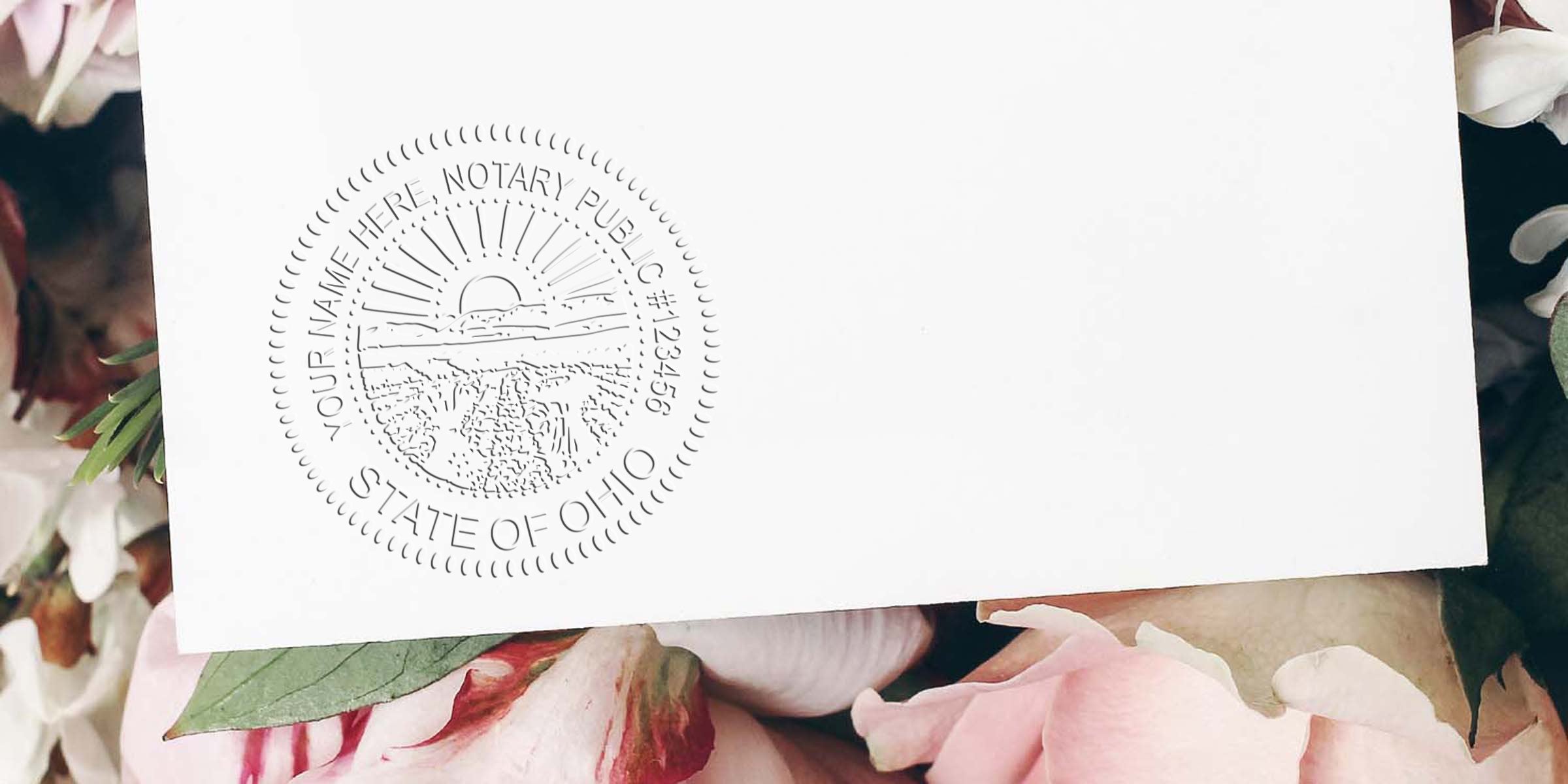 Embossed State of Ohio notary seal on white envelope placed atop pink peony flowers and green leaves, close-up stationery detail for legal documents and invitations