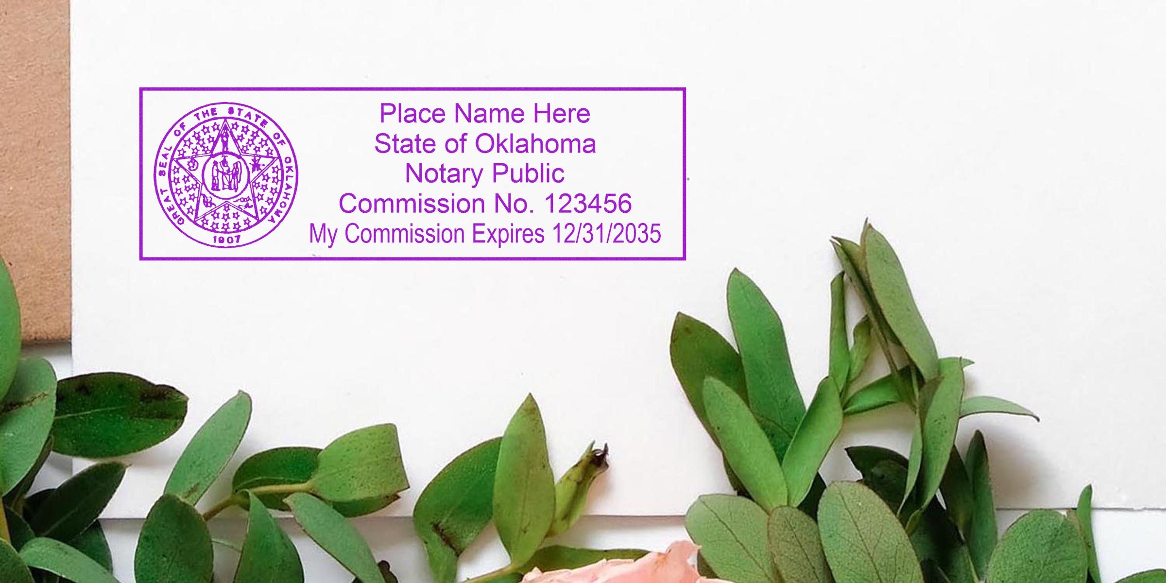 Purple Oklahoma notary public rectangular stamp on white envelope reading "Place Name Here, Commission No. 123456, Expires 12/31/2035" with green eucalyptus leaves and pink flower edge