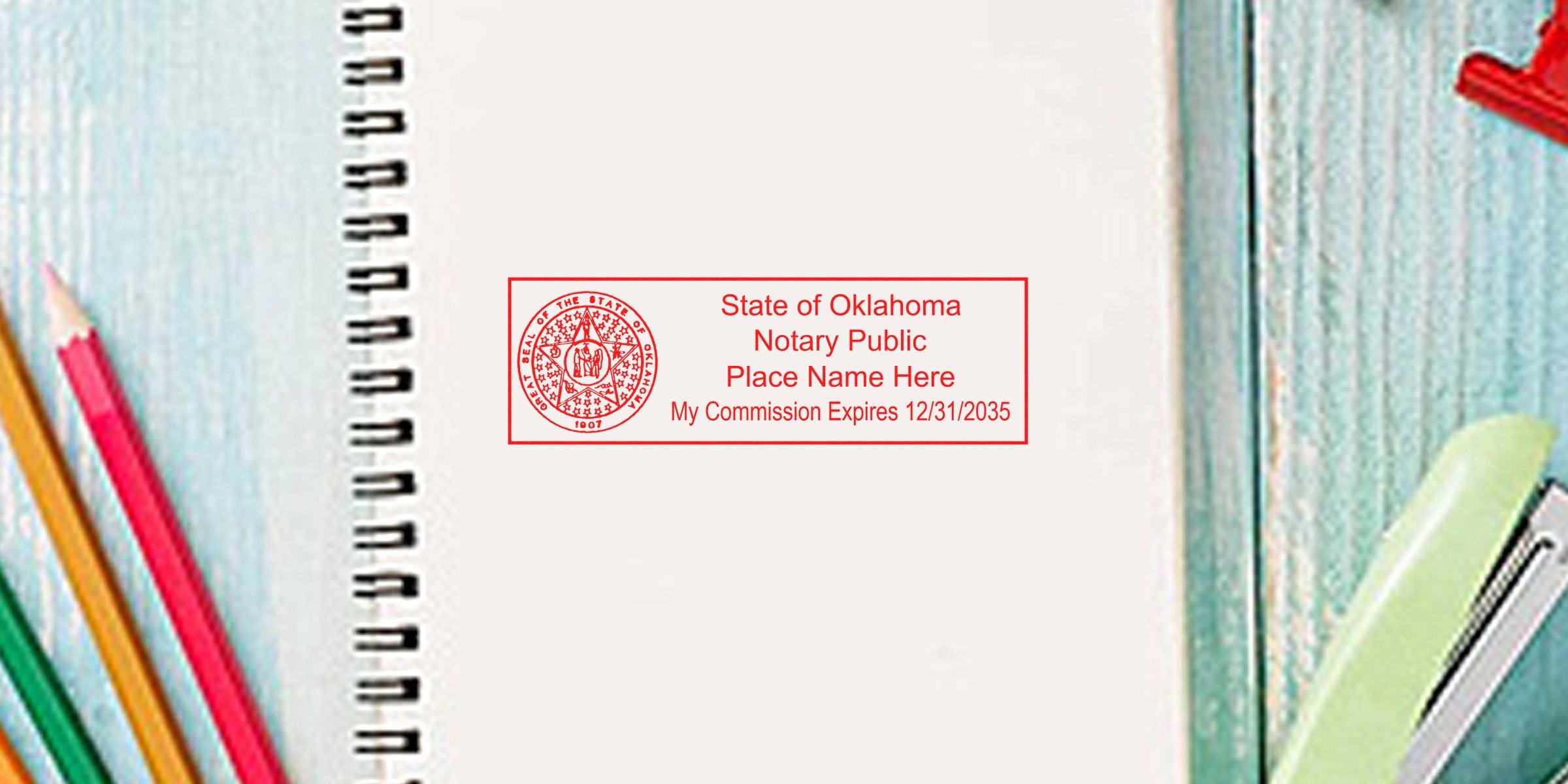 Red Oklahoma State of Oklahoma notary public stamp sample on blank spiral notebook page, customizable commission expiry date, colored pencils and stapler on wooden desk background