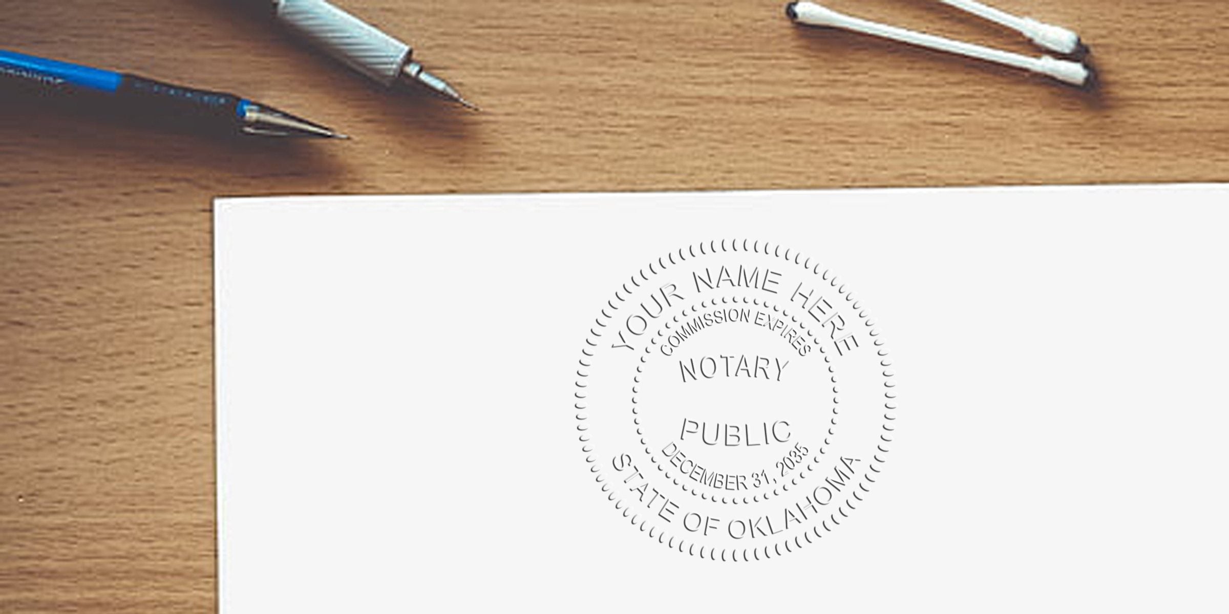 Embossed notary public seal on a white document on a wooden desk, accompanied by a pen, mechanical pencil and cotton swabs