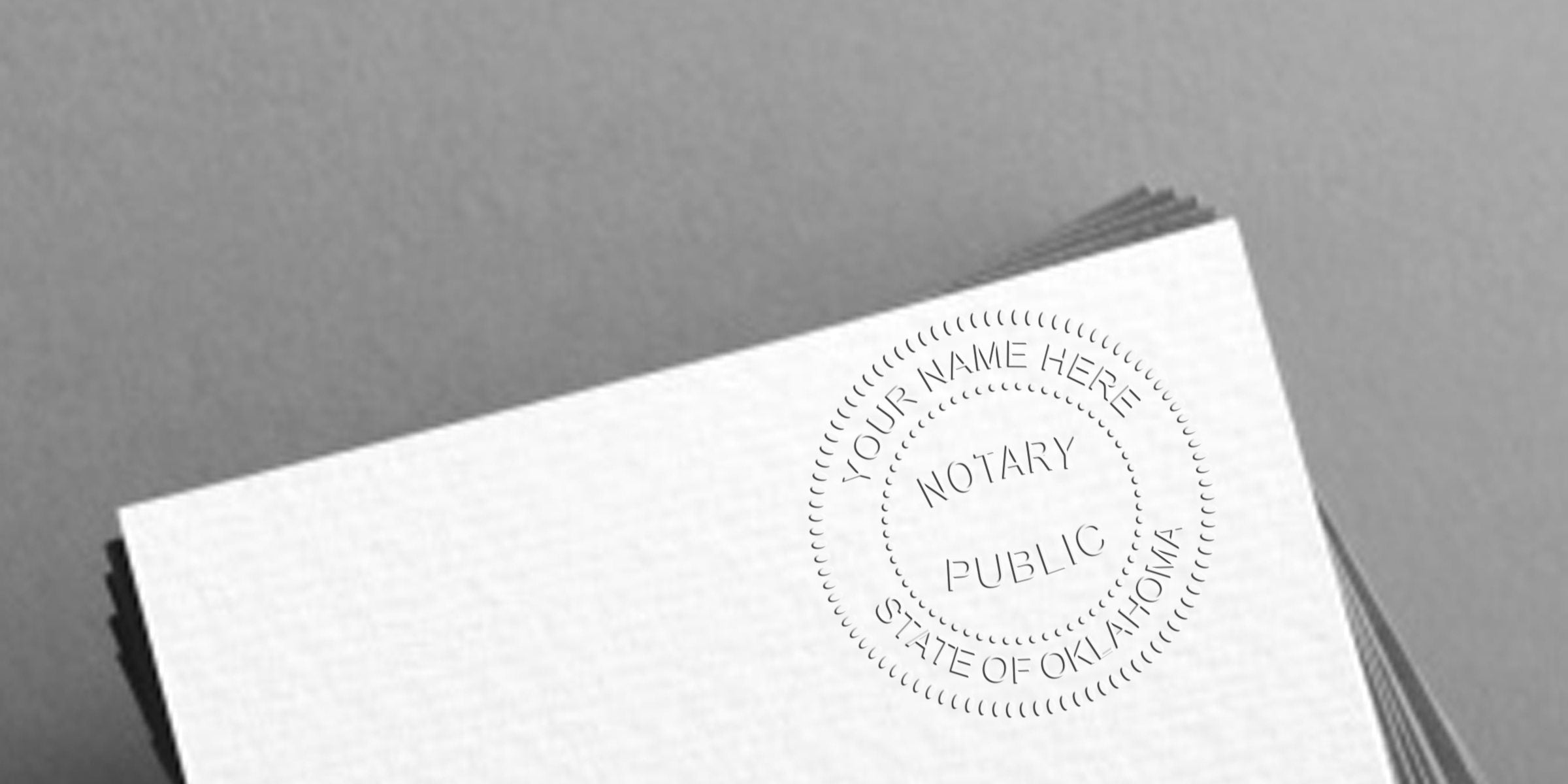 Stack of white papers with an embossed circular Notary Public seal reading "Your Name Here, State of Oklahoma" on the corner, close-up