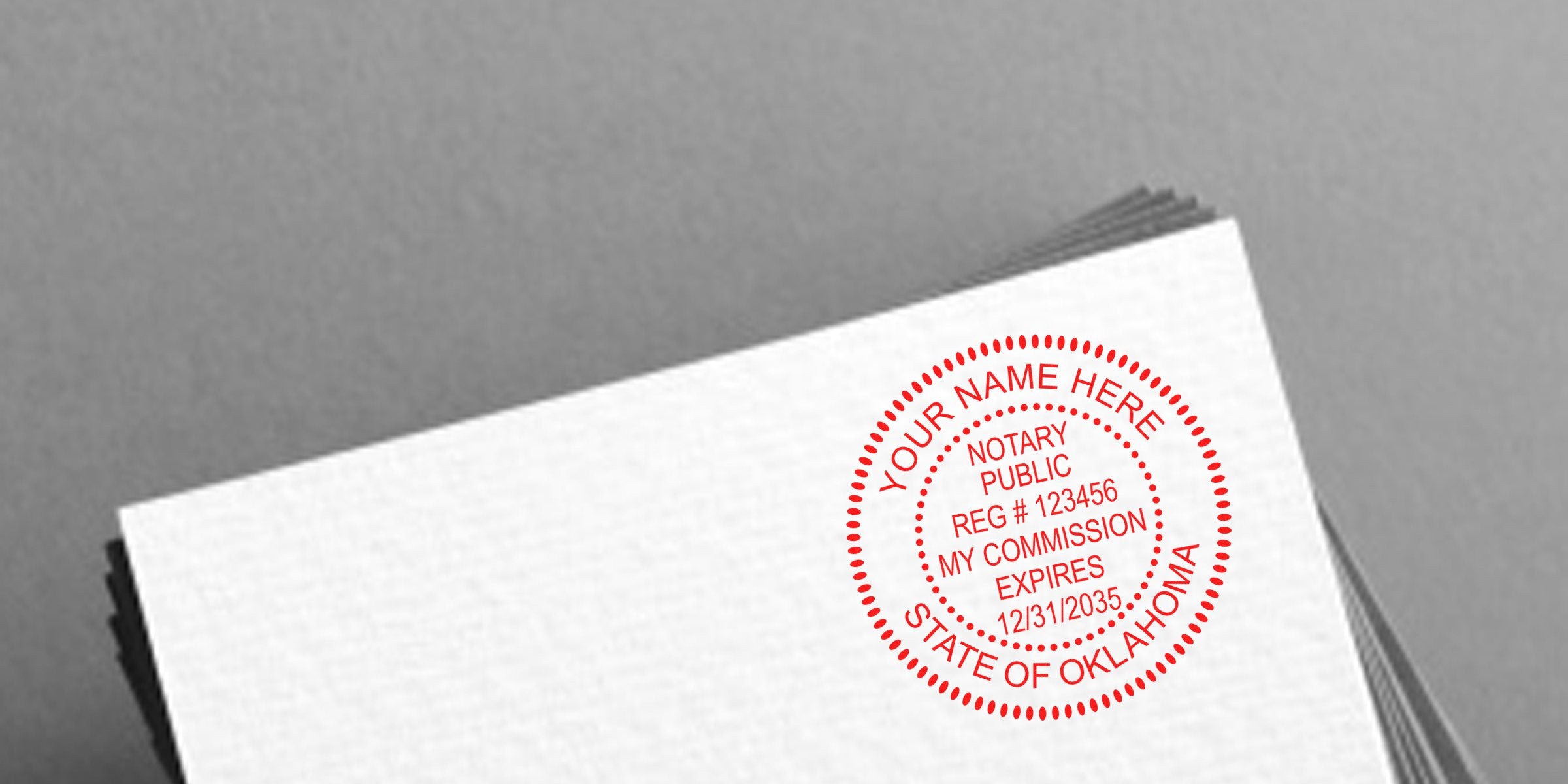 Stack of white papers with a red circular notary public stamp reading "YOUR NAME HERE, State of Oklahoma," registration number and commission expiration date.