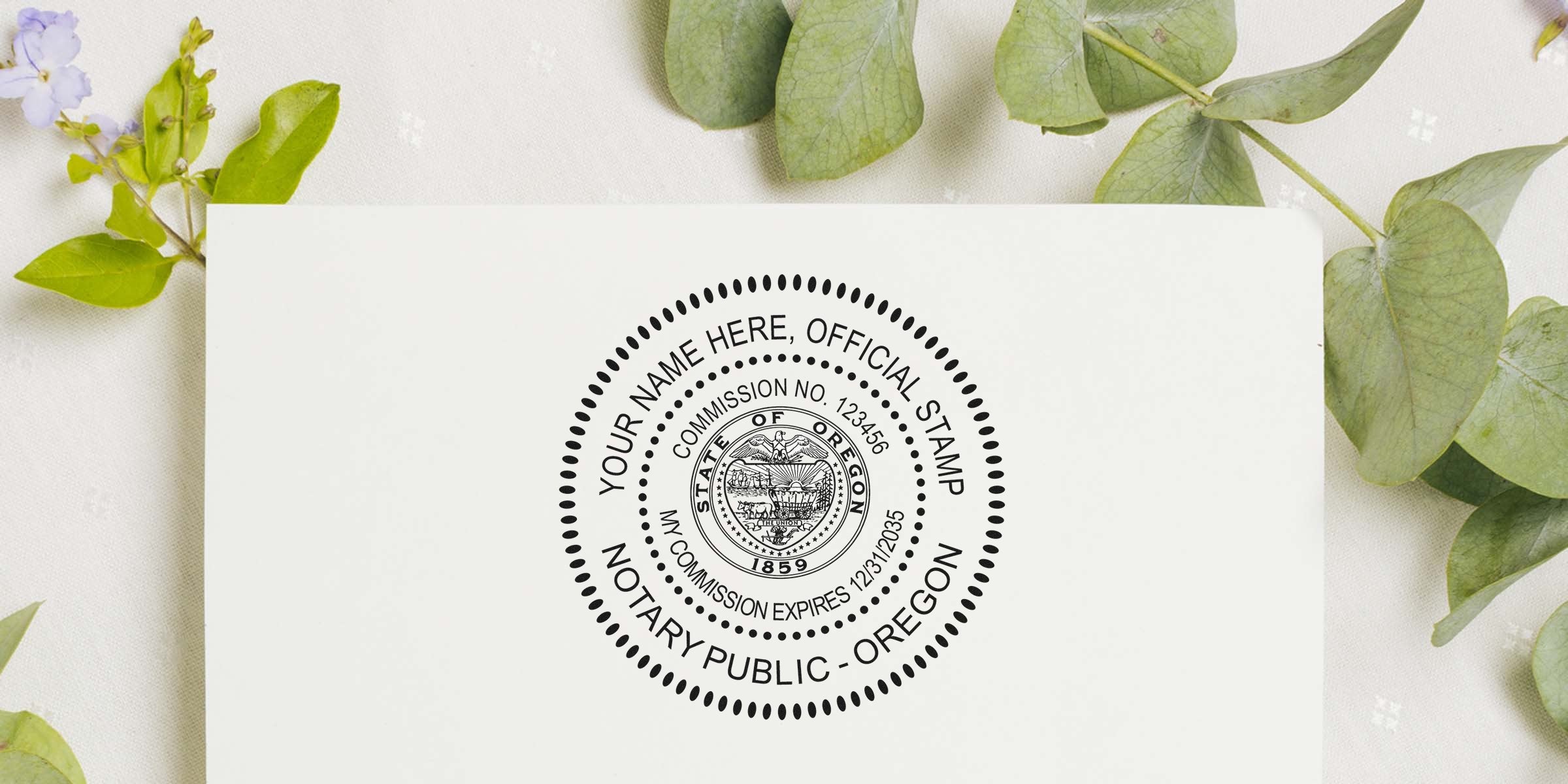 Close-up of a circular Oregon notary public official stamp mockup on white paper with a personalized name placeholder, surrounded by green eucalyptus leaves.