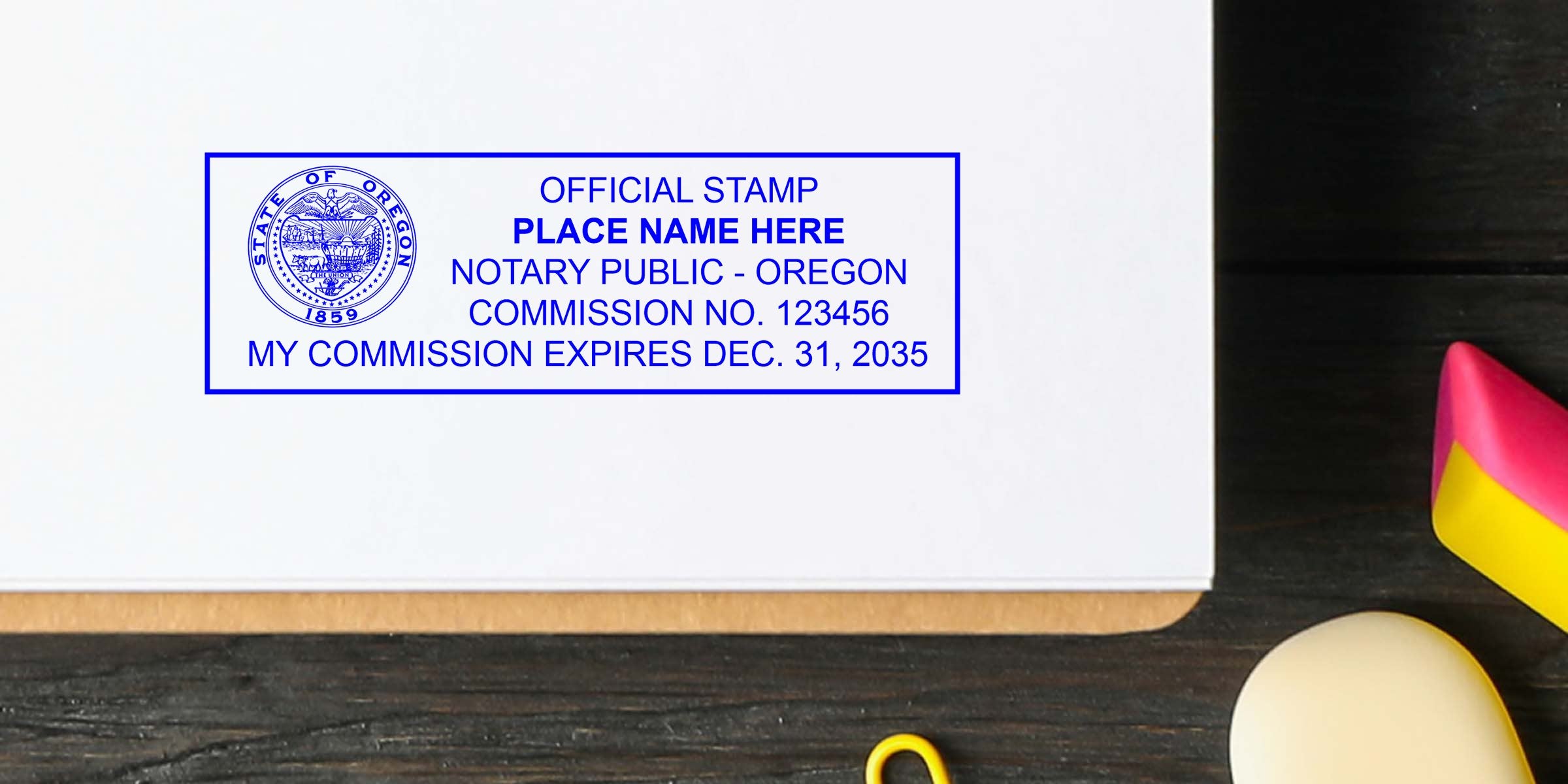 Blue rectangular Oregon notary public stamp on white paper showing state seal, commission number and expiration date on a clipboard over a dark wood desk with colorful desk accessories.