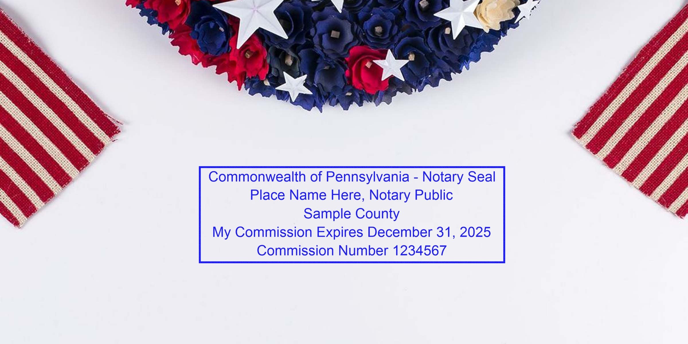 Top-view patriotic wreath of red, white and blue flowers with white stars, two red-and-white striped fabric flags, and a blue rectangular sample notary seal reading "Commonwealth of Pennsylvania - Notary Seal" on a white background.