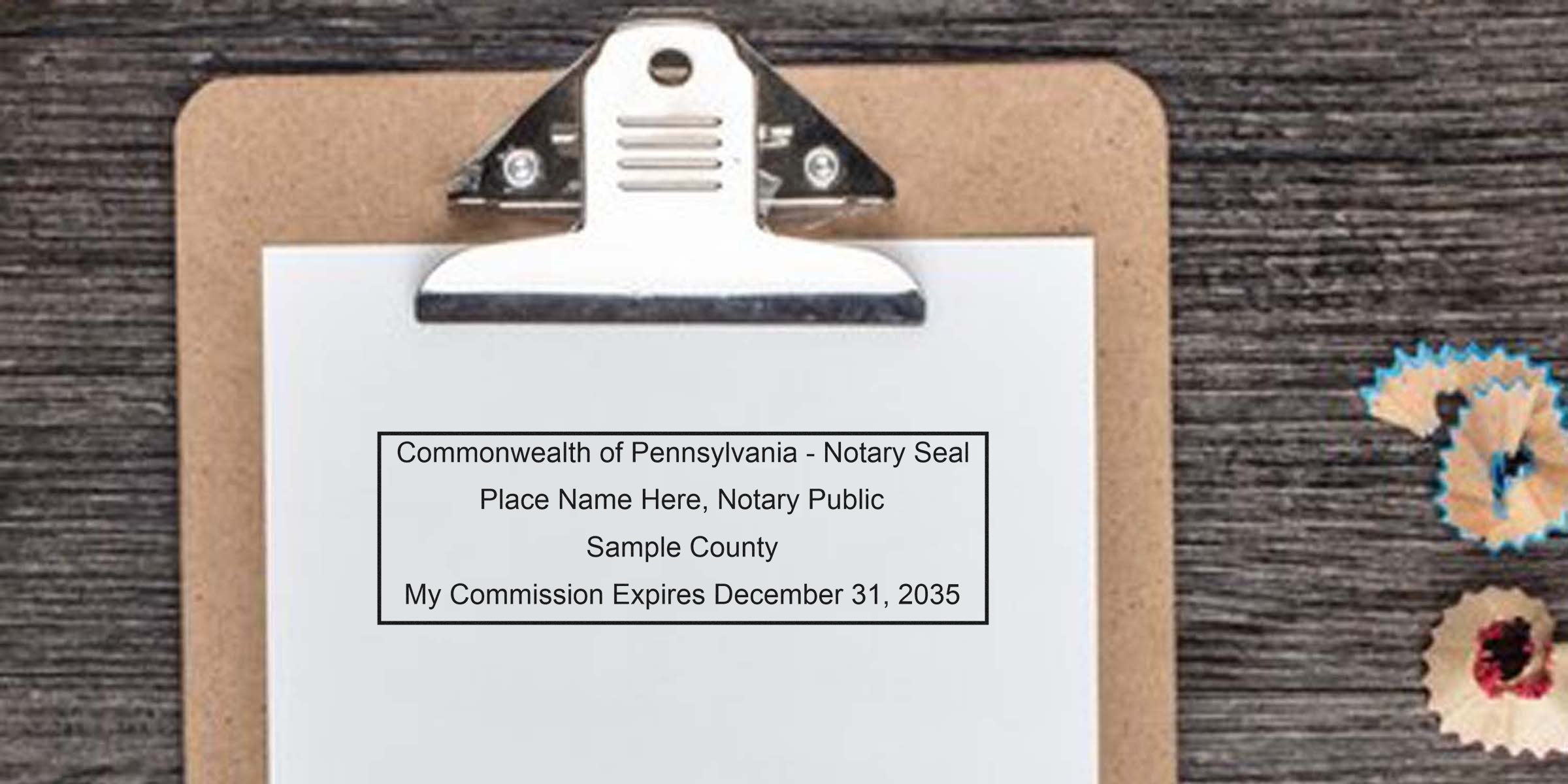 Clipboard with white paper showing a sample Commonwealth of Pennsylvania notary seal and commission expiration text, pencil shavings on a dark wood table.
