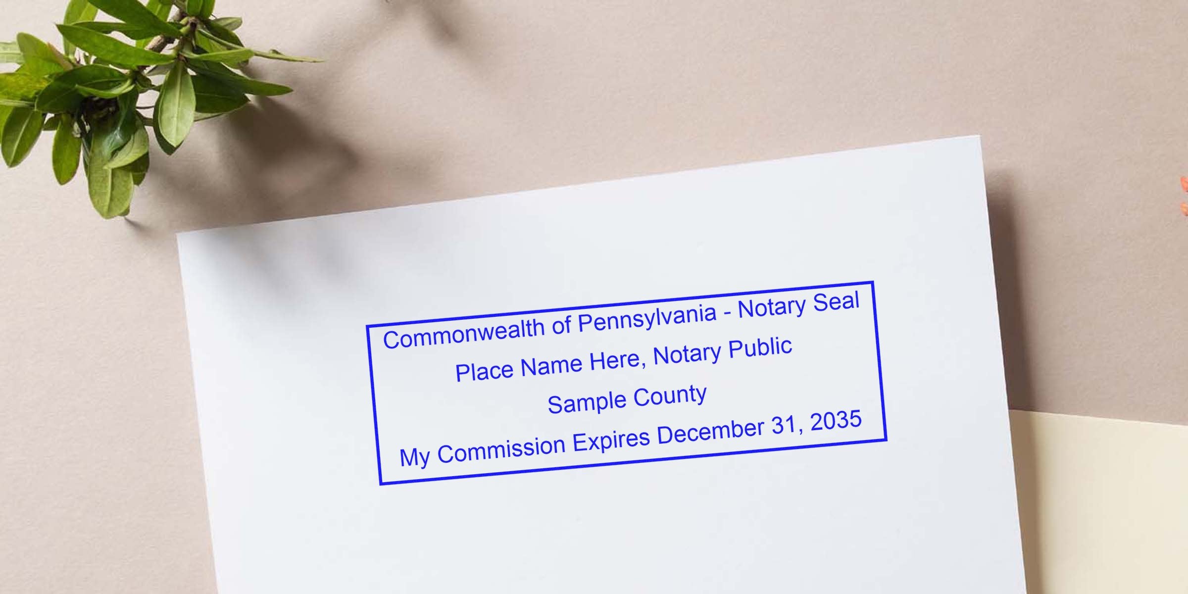 Blue rectangular Pennsylvania notary seal sample stamped on white paper reading "Place Name Here, Notary Public, Sample County" with nearby green plant on beige background