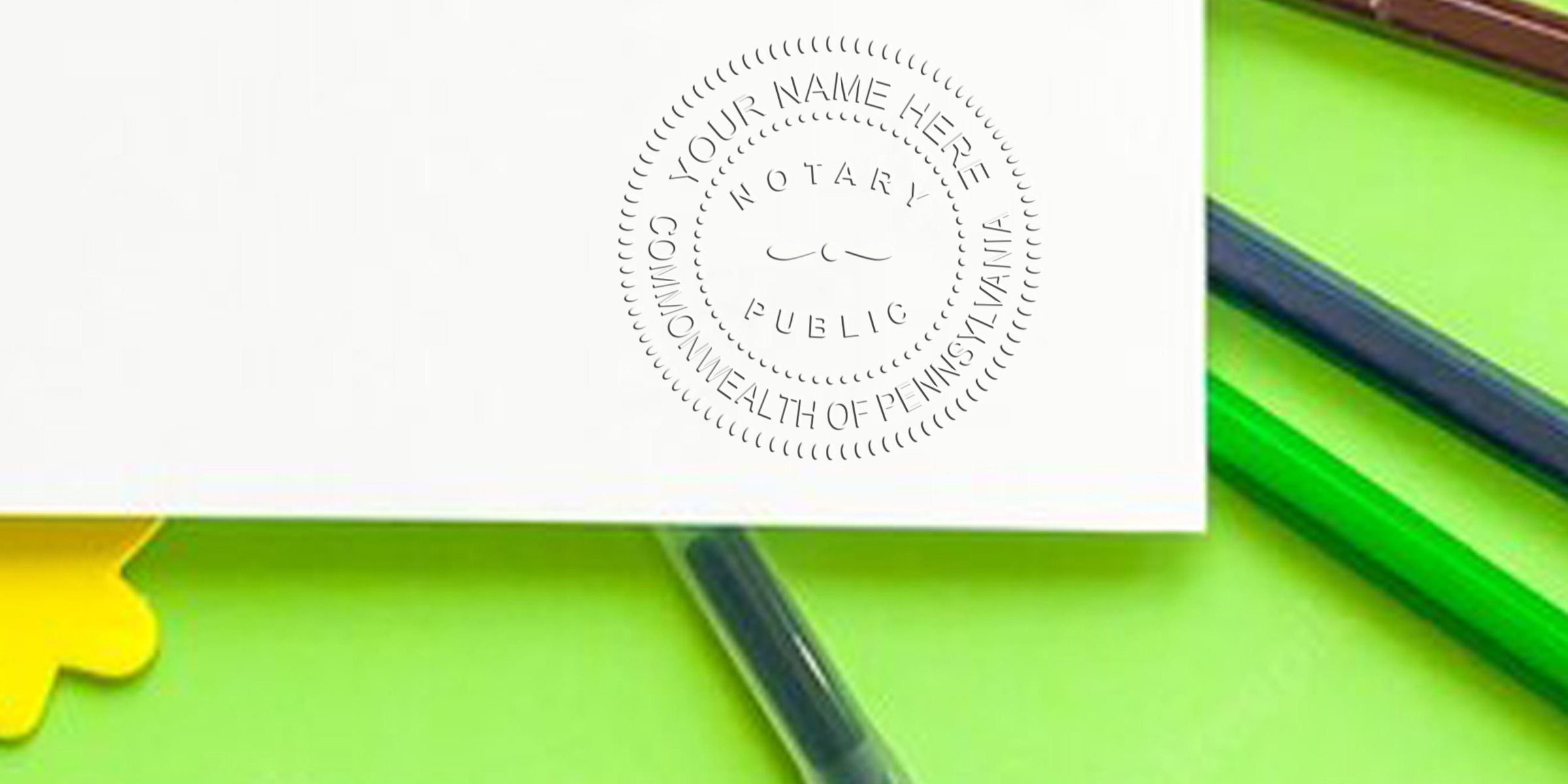 White paper with embossed "Notary Public Commonwealth of Pennsylvania" seal, resting on a bright green background with green and blue colored pencils and a yellow tab.