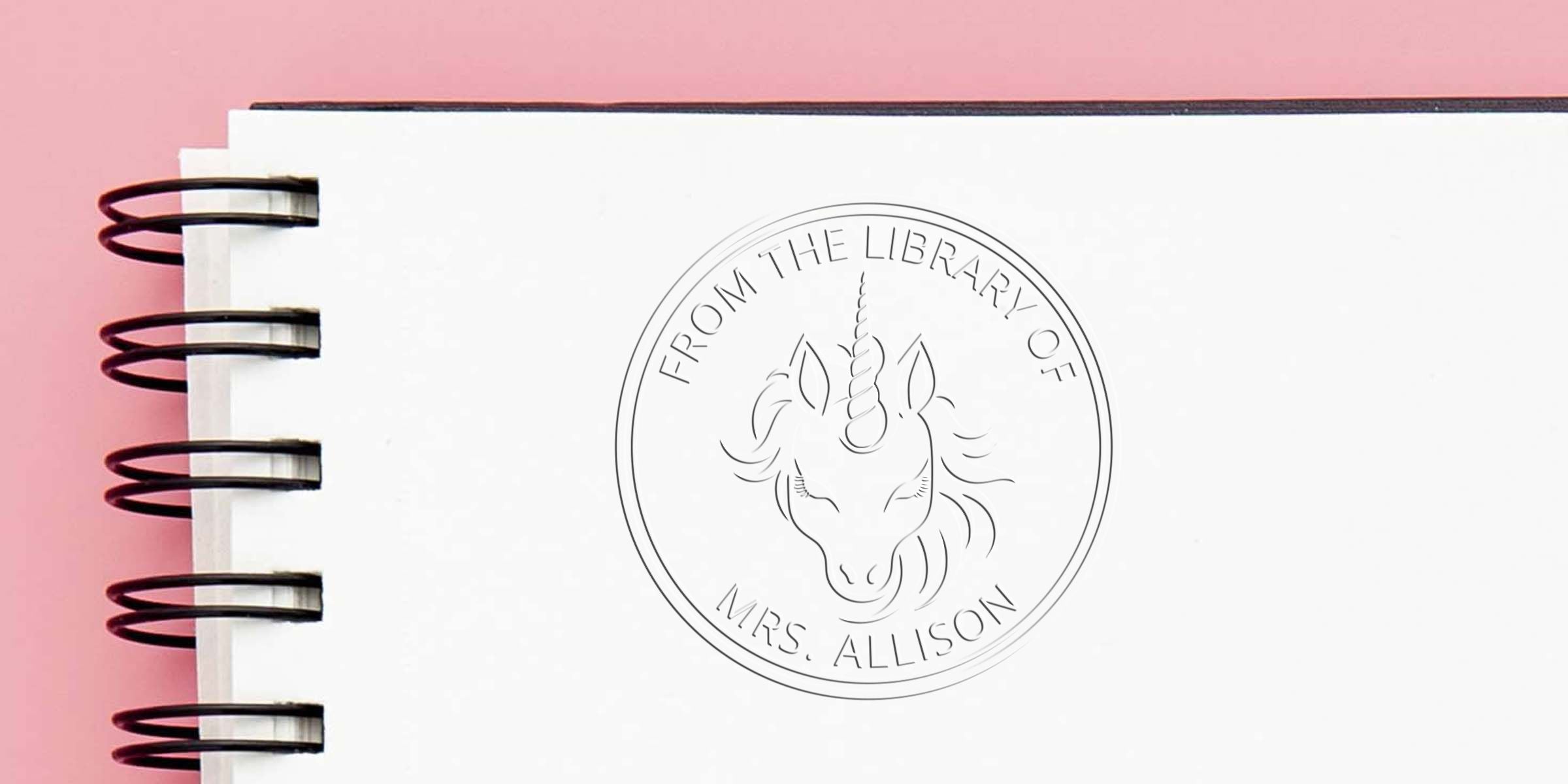 Line drawing of a unicorn head inside a circular coin with the text “FROM THE LIBRARY OF MRS. ALLISON” on a pink background.