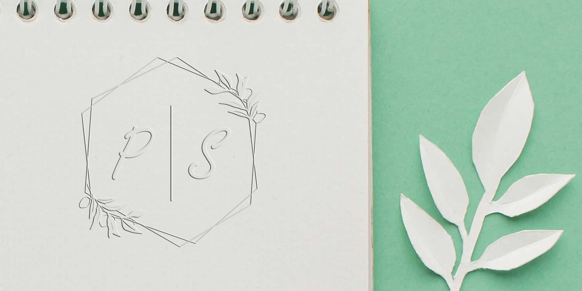 Monogram PS inside a geometric hexagon with delicate leaf accents on a light notebook page.