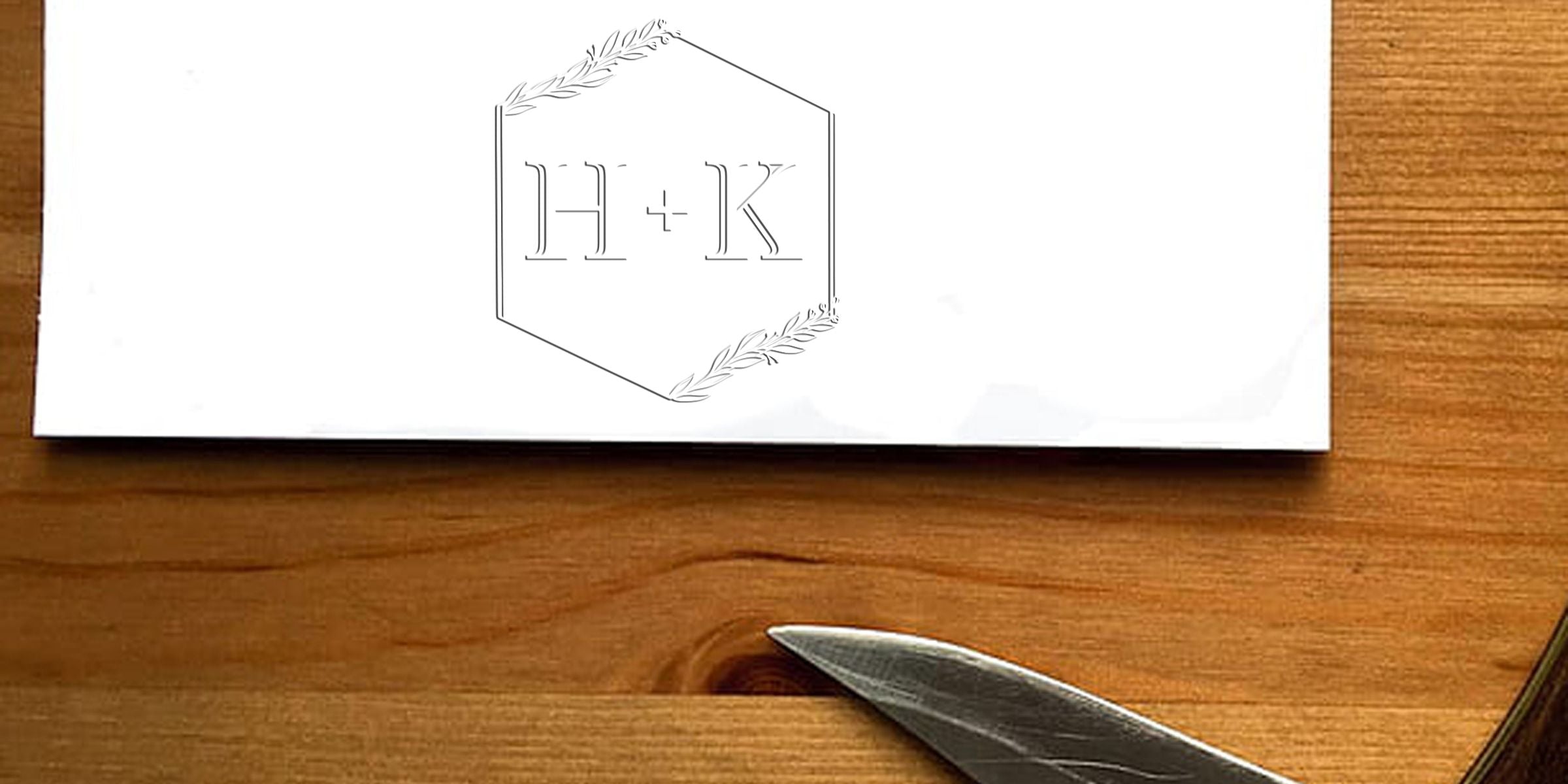 Logo with the letters "H+K" inside a hexagon and olive branch decorations.