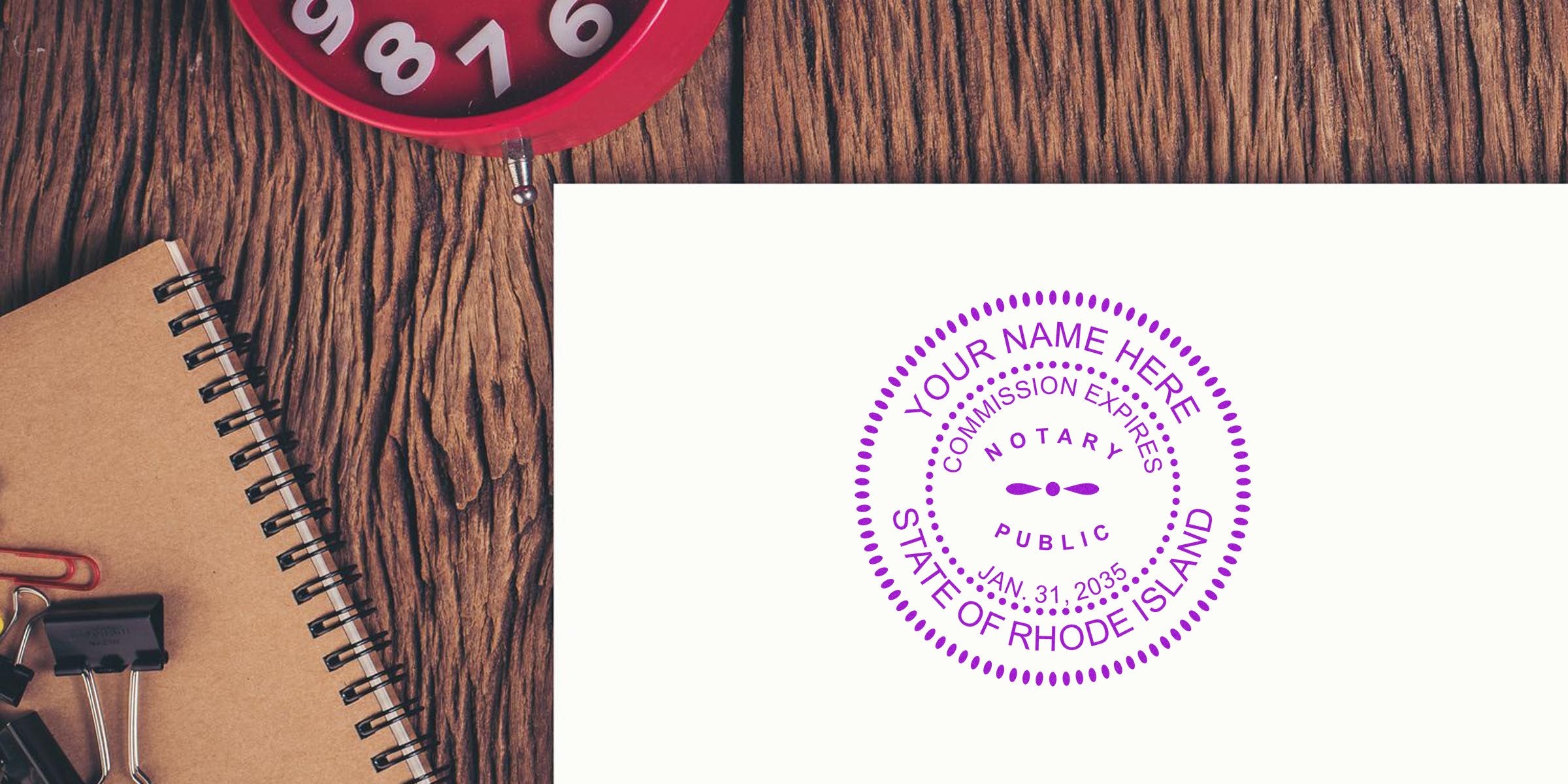 Overhead office desk with spiral notebook, binder clips, red alarm clock and white paper stamped with a purple "Notary Public State of Rhode Island" seal
