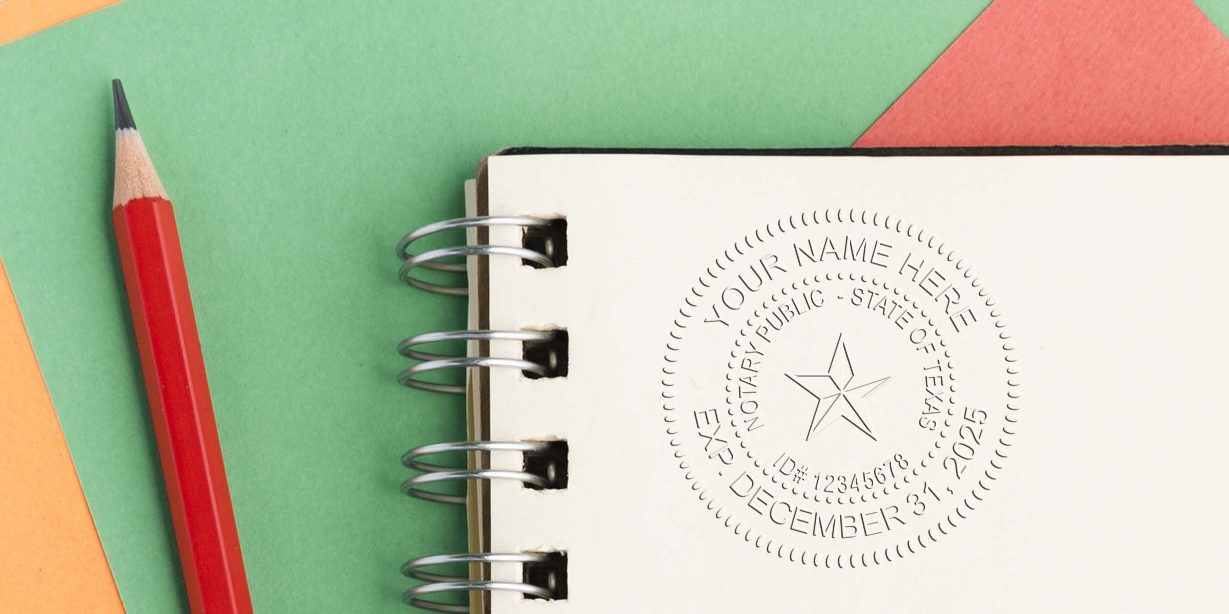 Spiral notebook with embossed notary seal impression and star emblem on white page beside red pencil on green and orange paper background