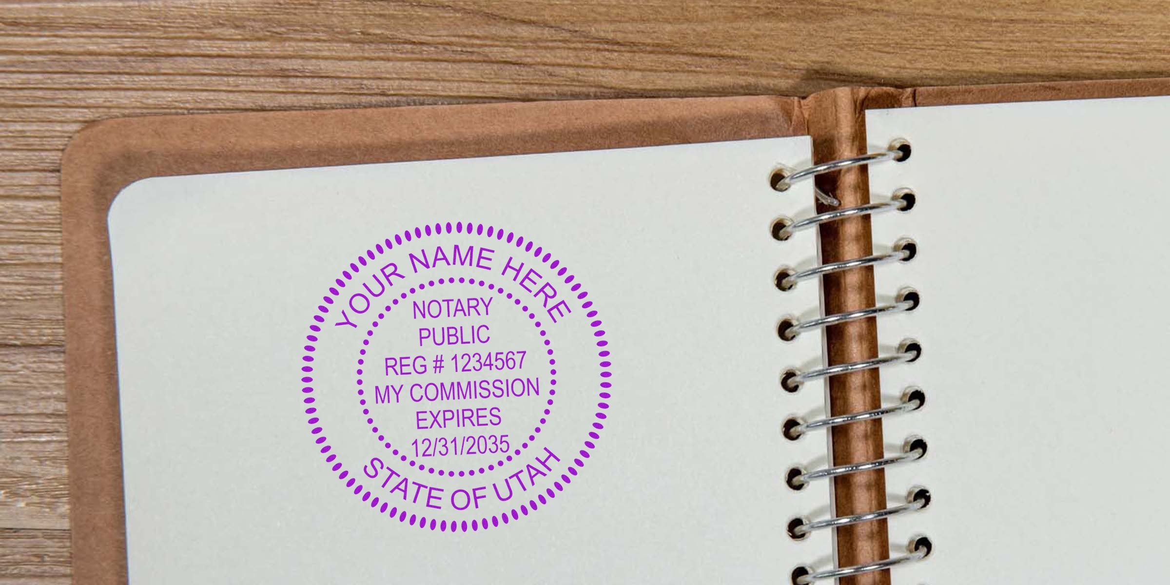 Purple circular notary public stamp impression on white spiral-bound notebook page beside wooden desk, customizable name and commission details visible