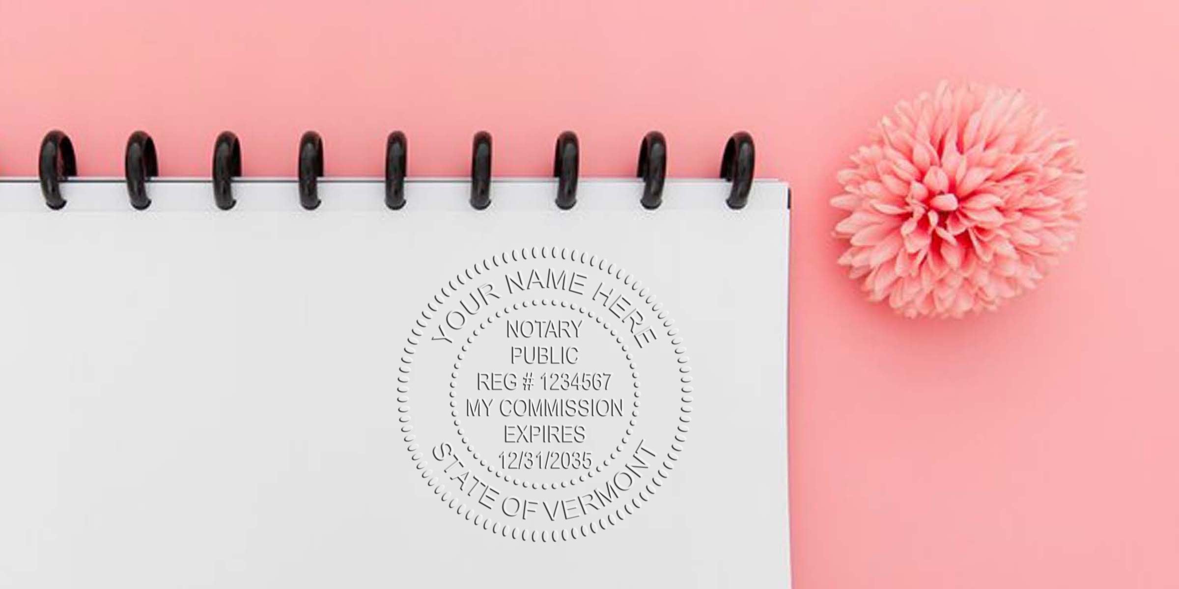Top view of spiral-bound white notebook embossed with Vermont notary public seal beside pink pompom on pastel pink background, flat lay office stationery image for notary, paperwork, and business branding.