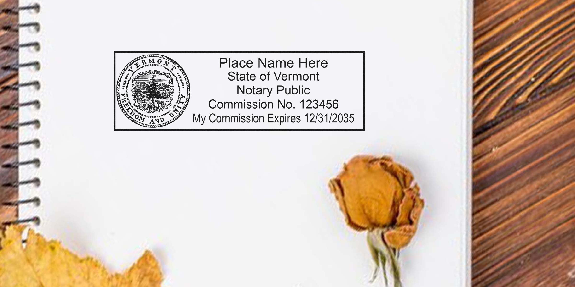 Vermont notary public stamp template on spiral notebook page showing state seal, commission number and expiration date, with dried rose and autumn leaf on wooden table — flat lay office stationery photo