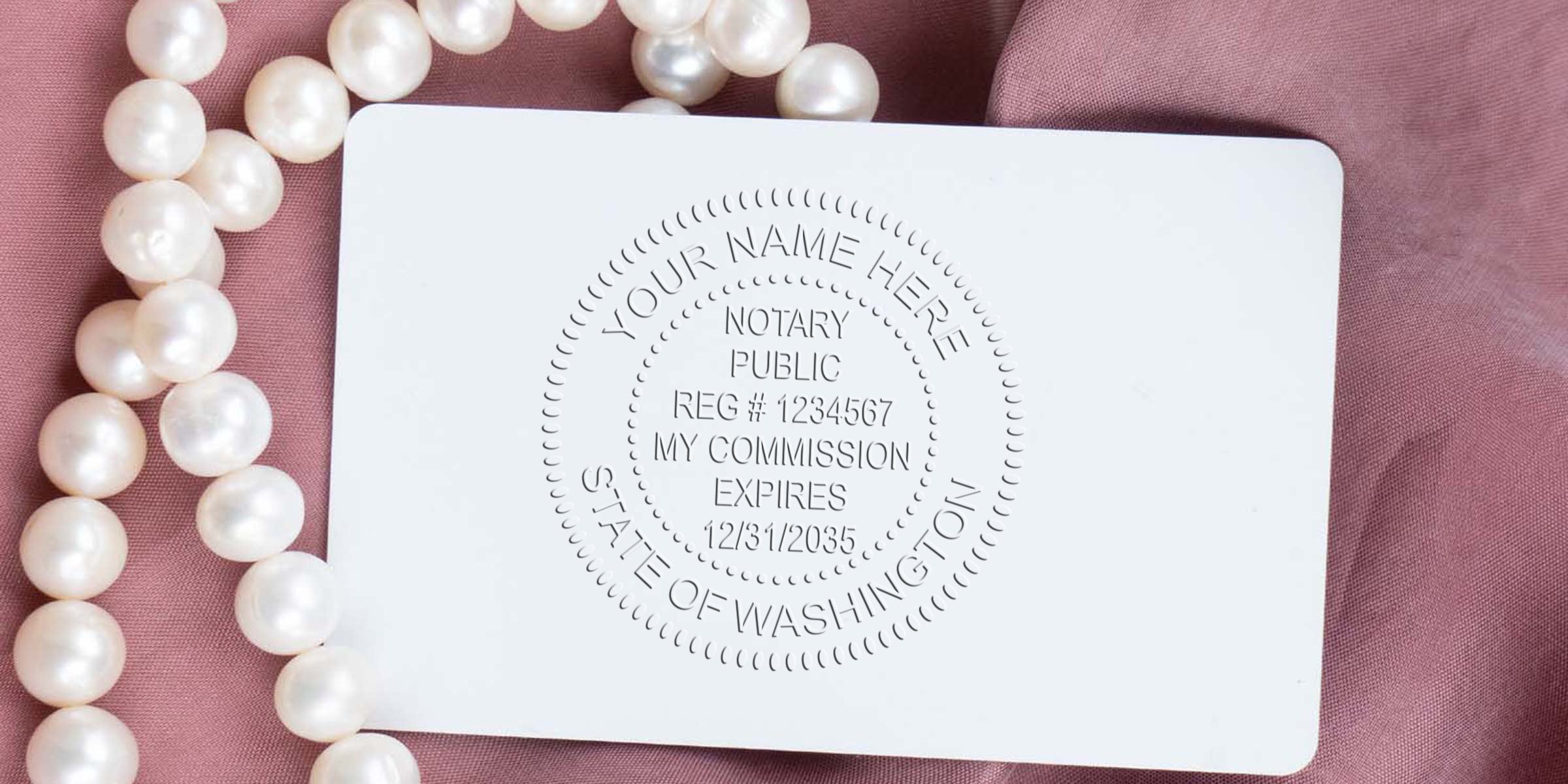 Embossed notary public seal on a white card showing registration and commission expiry details, placed on pink fabric beside a pearl necklace.