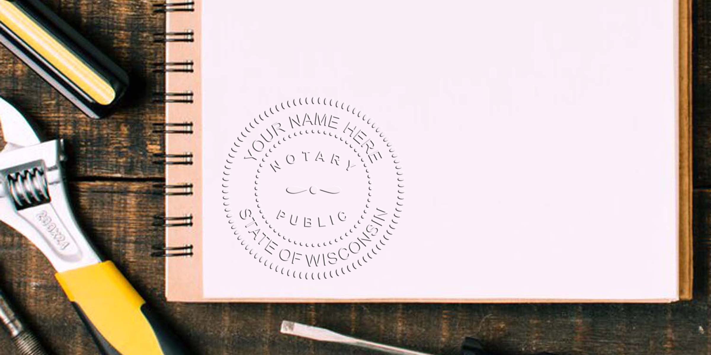 Notary public embosser stamp impression reading "Your Name Here, Notary Public, State of Wisconsin" on blank spiral notebook page beside wrench and screwdriver on rustic wooden workbench