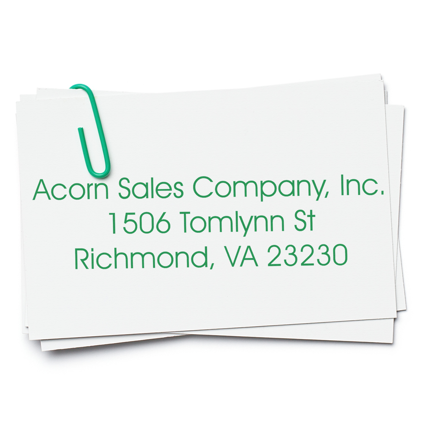 Image of a stack of cards with a green paperclip, featuring a custom address stamp for Acorn Sales Company, Inc. Blog post: The Importance of Custom Address Stamps for Office Efficiency Feature Image.