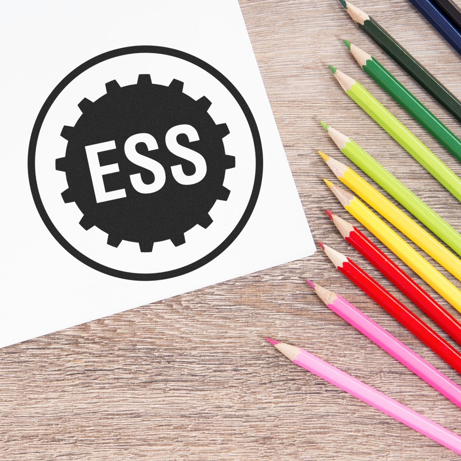 Office Stamp Fonts Unveiled: Enhance Your Professional Image Feature Image - ESS stamp on paper beside colorful pencils on a wooden desk.