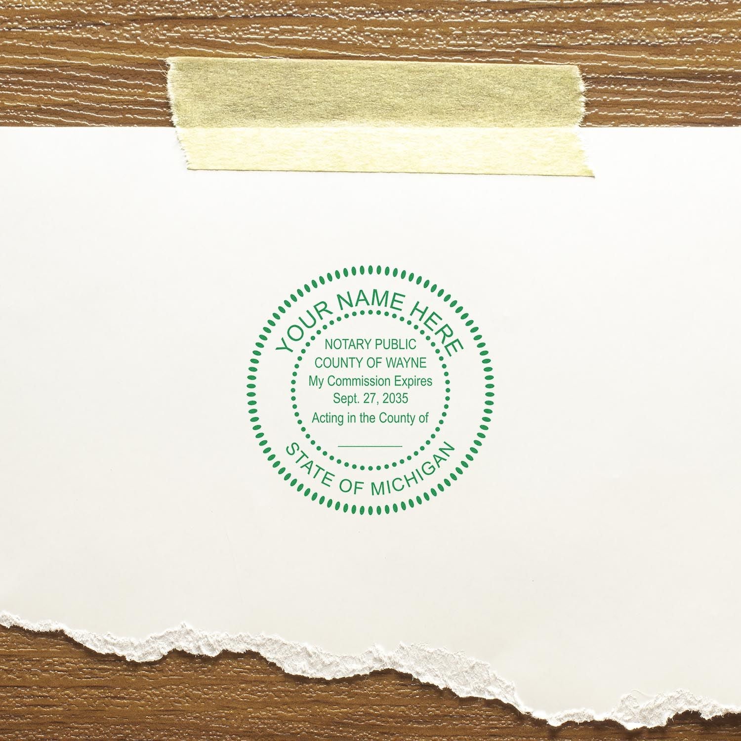 Michigan Notary Supplies Blog Post Feature Image: A green notary stamp on white paper taped to a wooden surface, displaying notary details.