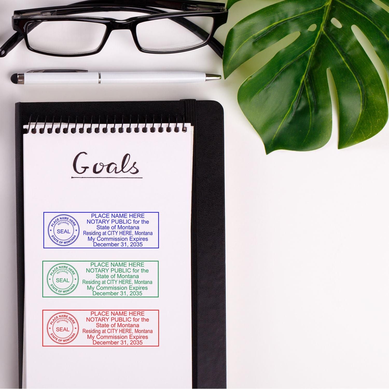 Montana Notary Supplies Blog Post Feature Image: Notepad with 'Goals' written, three notary stamps, glasses, pen, and a green leaf.