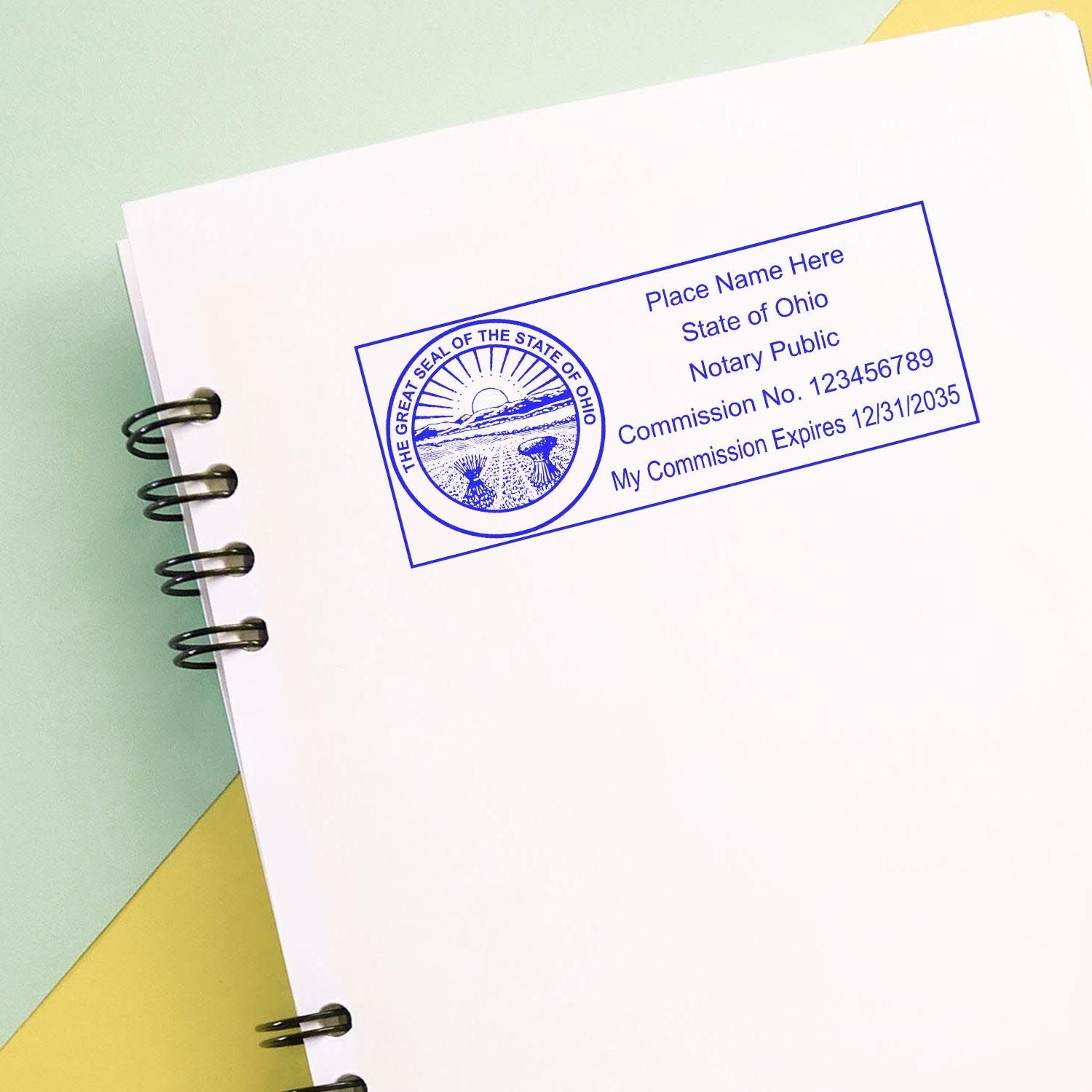 Ohio Notary Supplies Blog Post Feature Image: Rectangular notary stamp on a spiral-bound notebook with Ohio state seal and commission details.