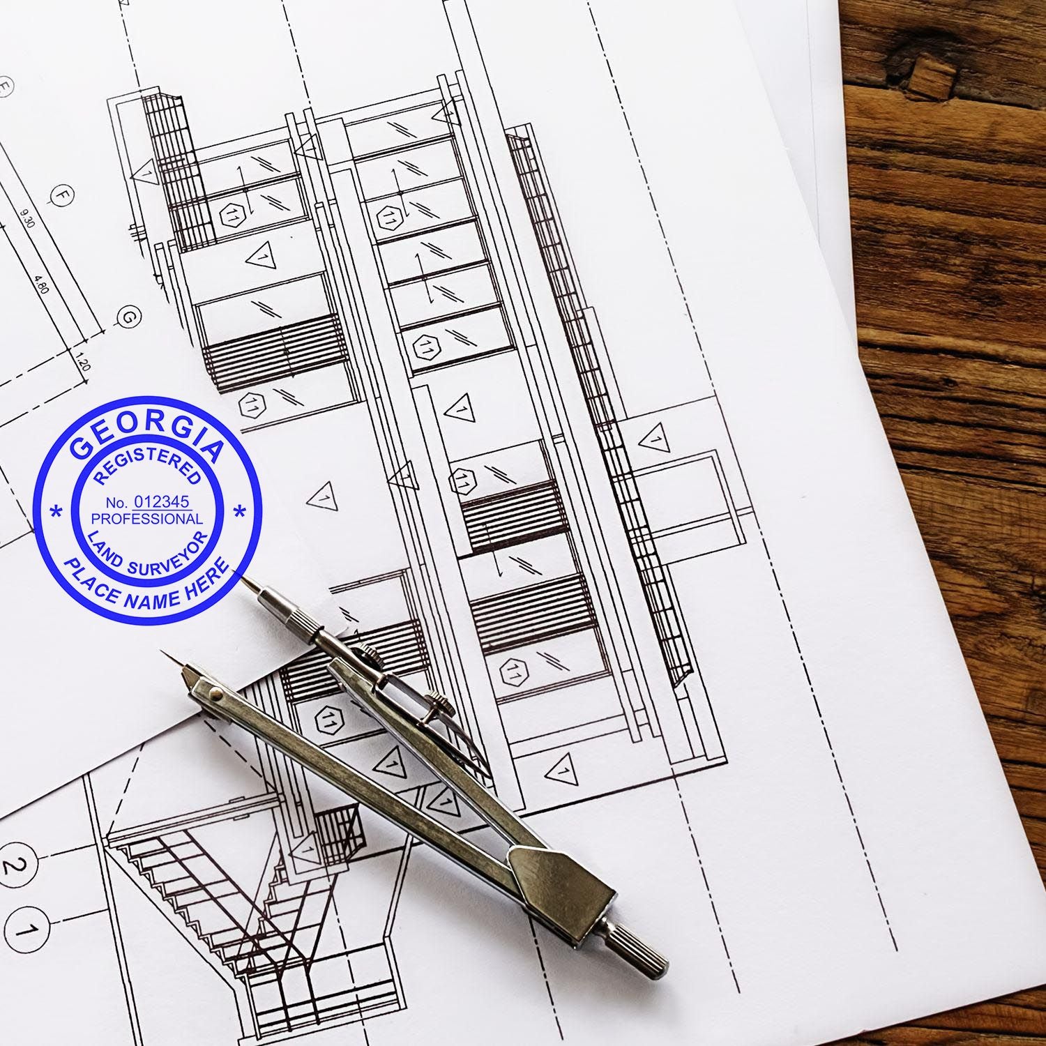 Blueprints with a Georgia Land Surveyor Stamp, compass, and pencil on a wooden table. Blog post: Georgia Land Surveyor Stamp.