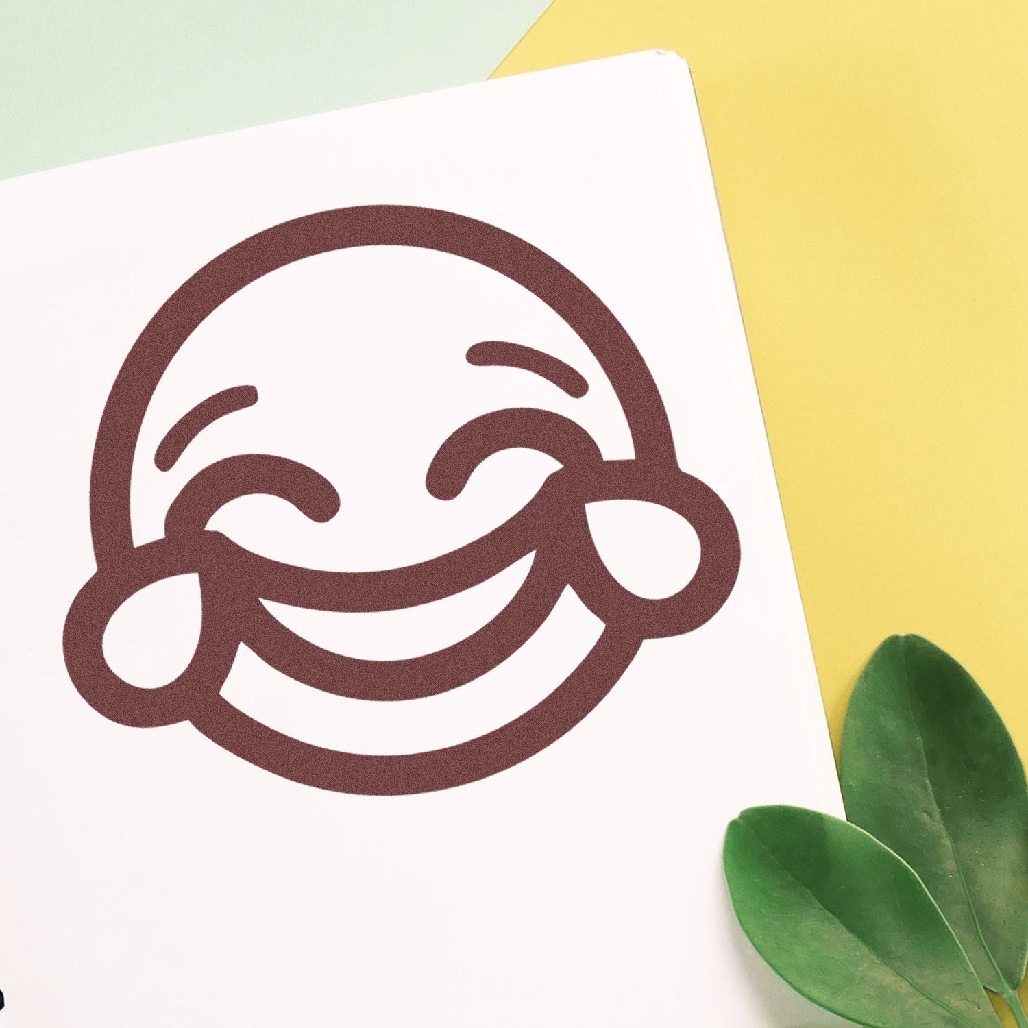 Self-Inking Cheeky Grin Emoji Stamp on paper, featuring a bold, smiling face with closed eyes and rosy cheeks, perfect for adding fun to documents and crafts.