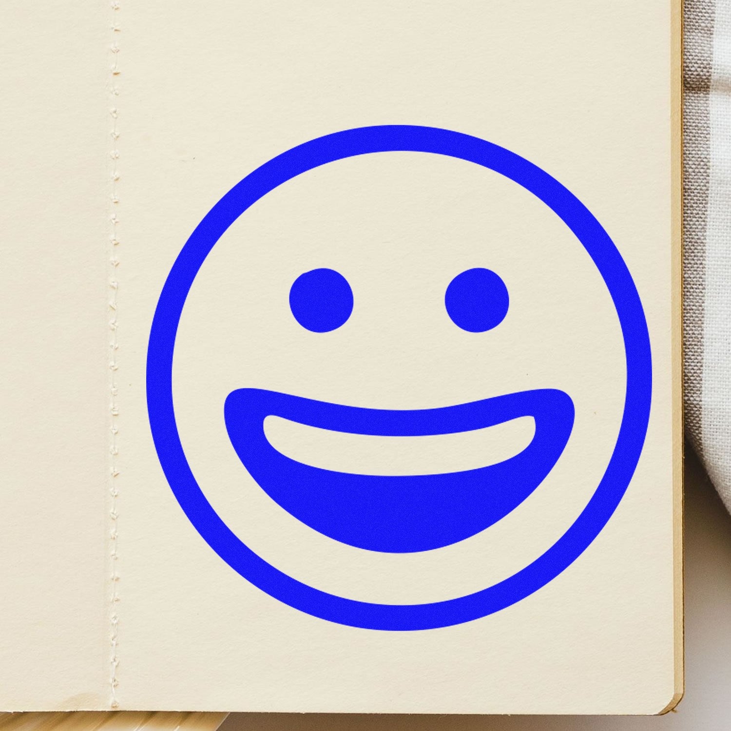 Self-Inking Classic Grin Emoji Stamp in blue ink on paper, showcasing a cheerful smiley face design. Perfect for adding fun and personality to notes and documents.