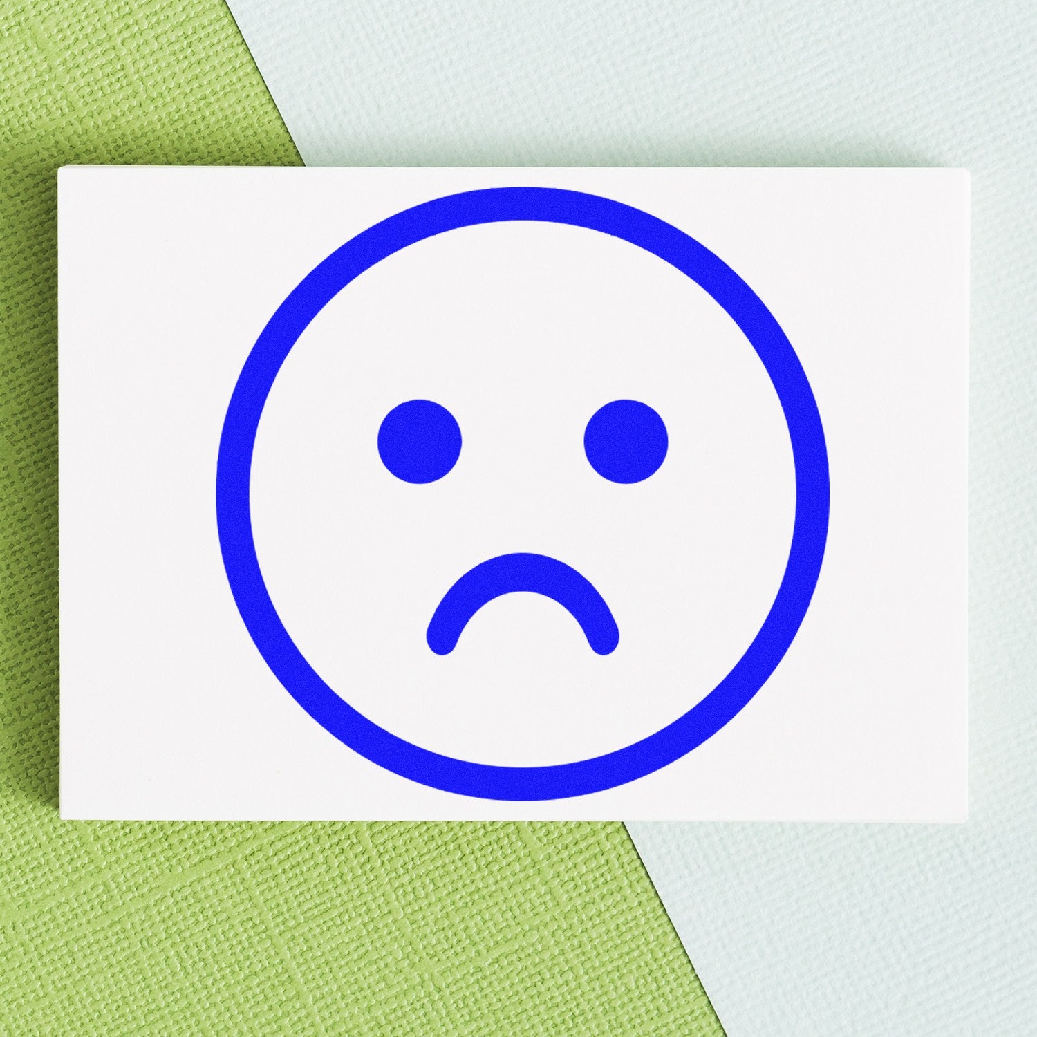 Self-Inking Sad Sam Emoticon Stamp with a blue sad face design on a white background, perfect for adding a touch of emotion to your documents.