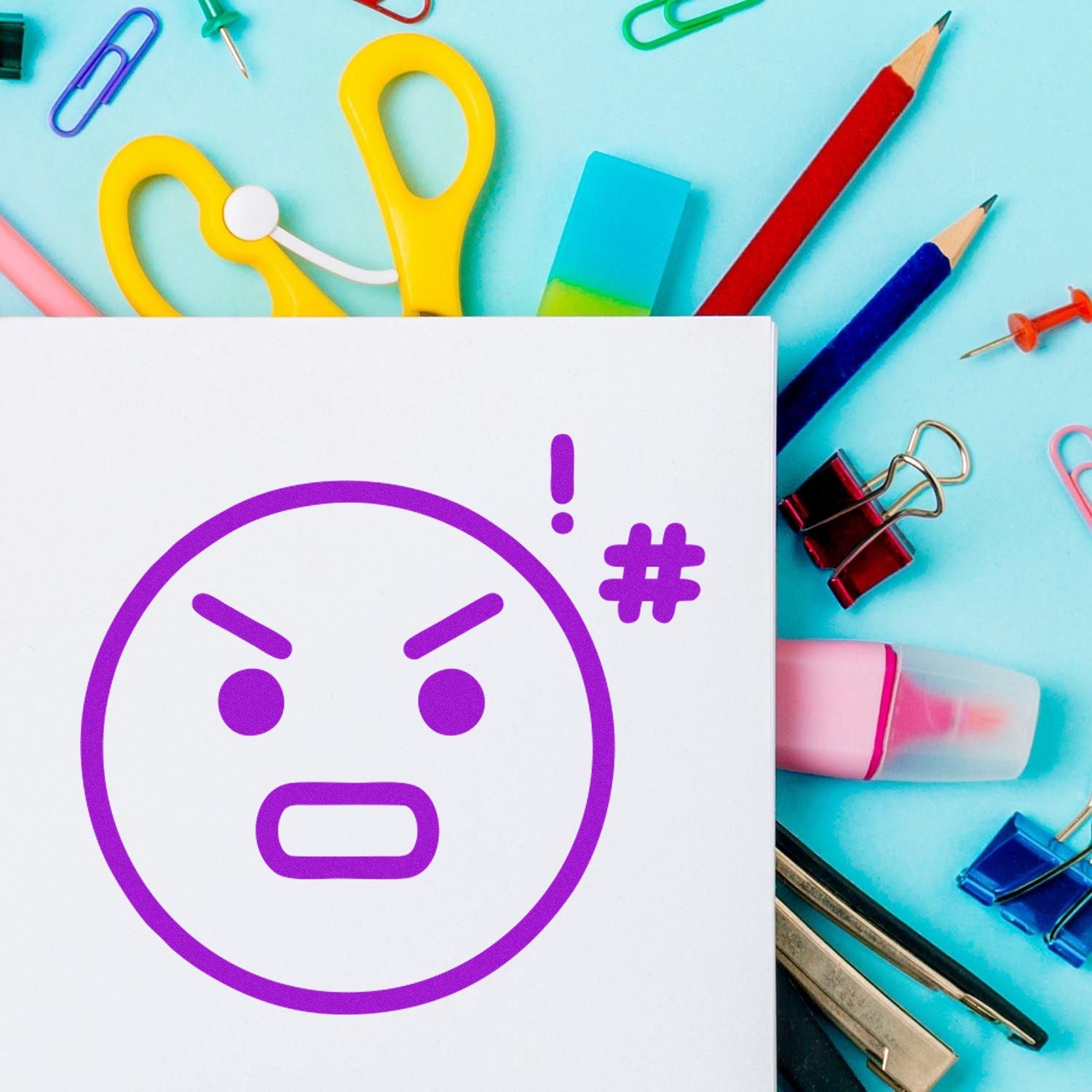 Self-Inking Angry Alfie Emoji Stamp with a purple angry face design, surrounded by colorful stationery on a light blue background. Perfect for adding fun expressions to your documents.