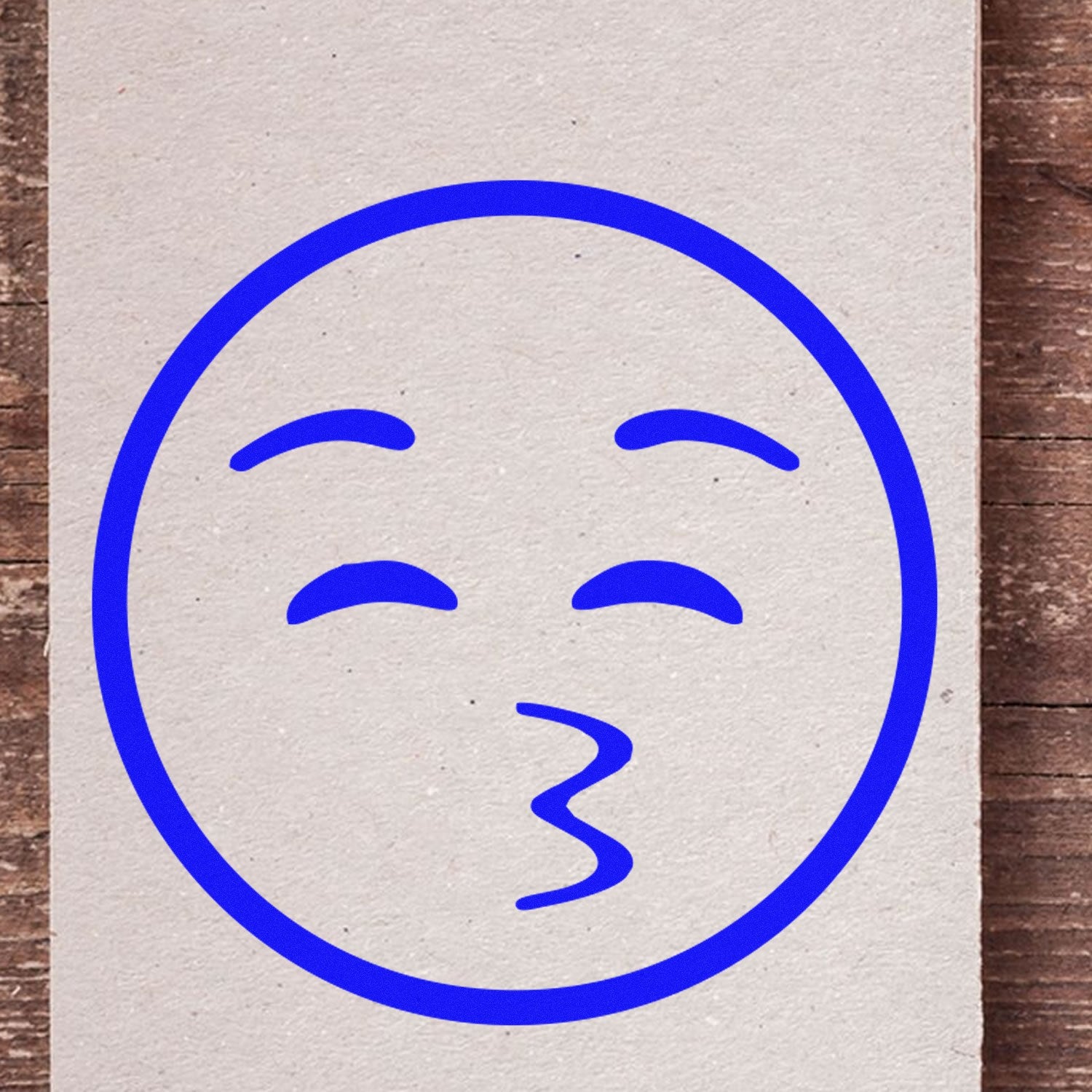 Wood Handle Whistling Willie Emoji Rubber Stamp on paper, featuring a blue whistling face design. Perfect for crafting and personalizing stationery.