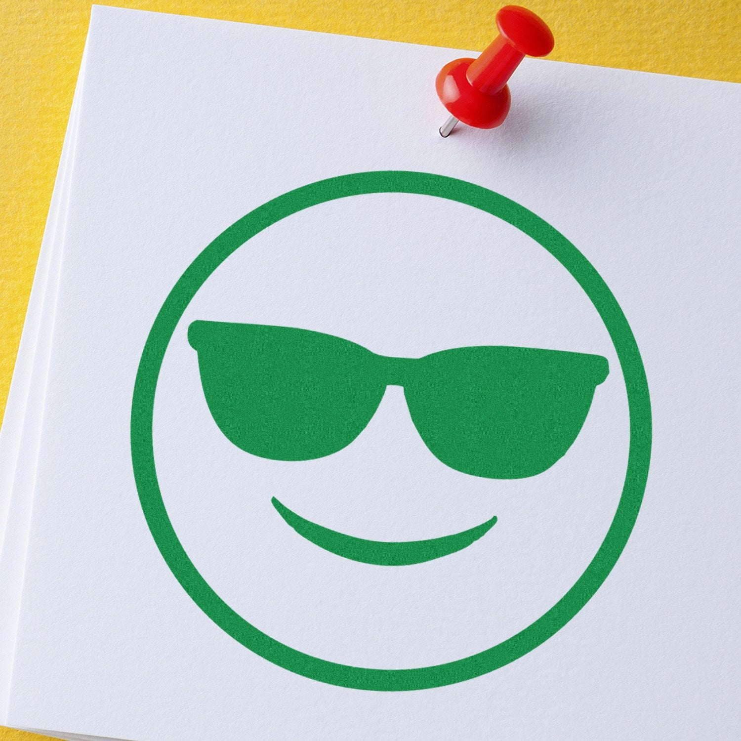 Wood Handle Cool Carl Emoji Rubber Stamp imprint showing a green emoji with sunglasses on white paper, pinned with a red pushpin.