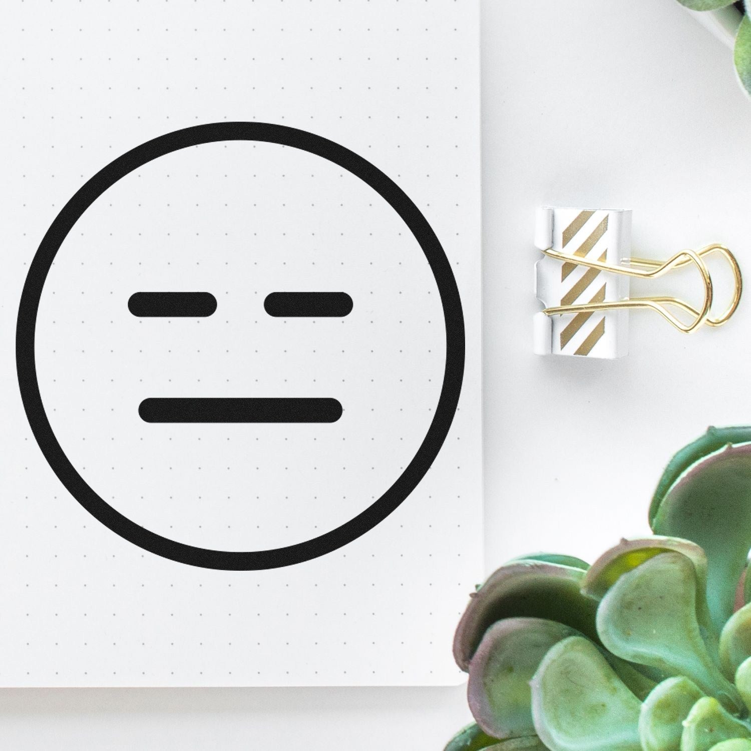 Self-Inking Expressionless Eddie Emoji Stamp on dotted paper, featuring a simple, neutral face design. Perfect for adding a touch of humor to documents and crafts.