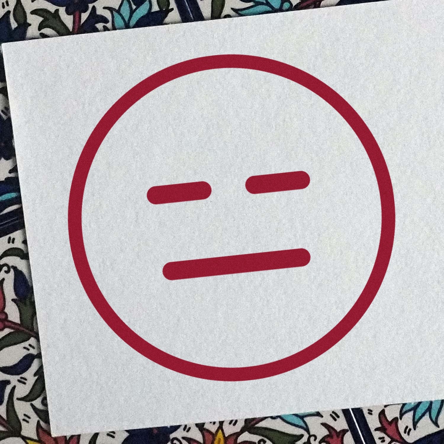 Wood Handle Expressionless Eddie Emoji Rubber Stamp on paper, featuring a simple, red expressionless face design. Perfect for adding a unique touch to crafts and stationery.