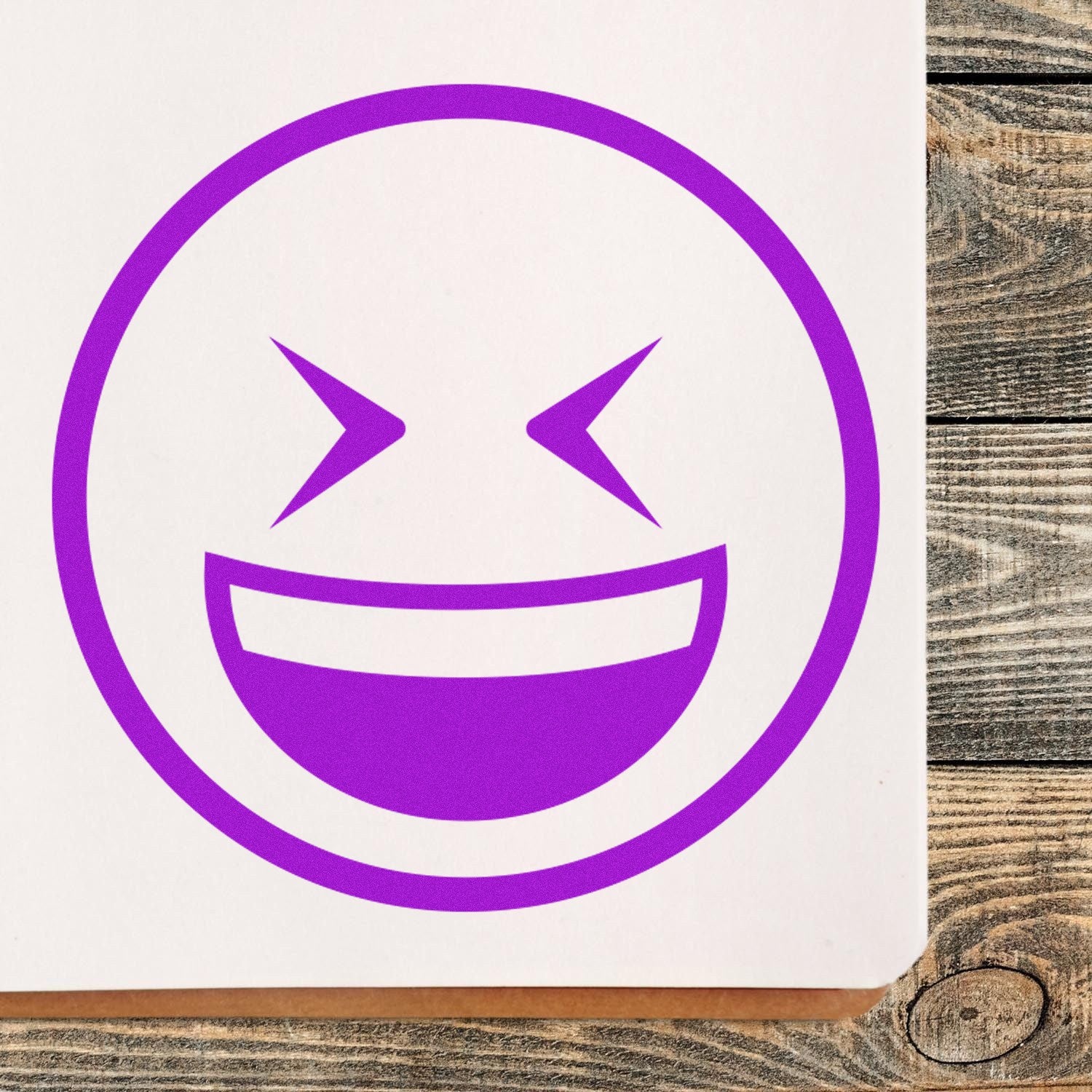 Wood Handle Excited Squint Emoji Rubber Stamp on paper, featuring a vibrant purple excited squint emoji design. Perfect for adding fun and personality to crafts and stationery.