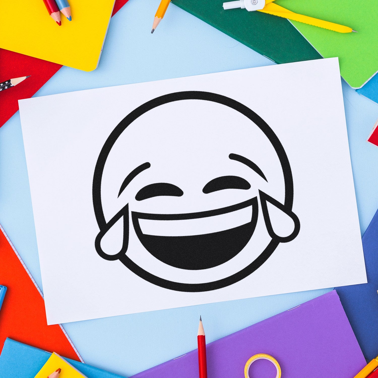 Image of the Self-Inking Tearful Giggles Emoji Stamp on colorful paper, showcasing a laughing emoji with tears. Perfect for adding fun and emotion to crafts and documents.