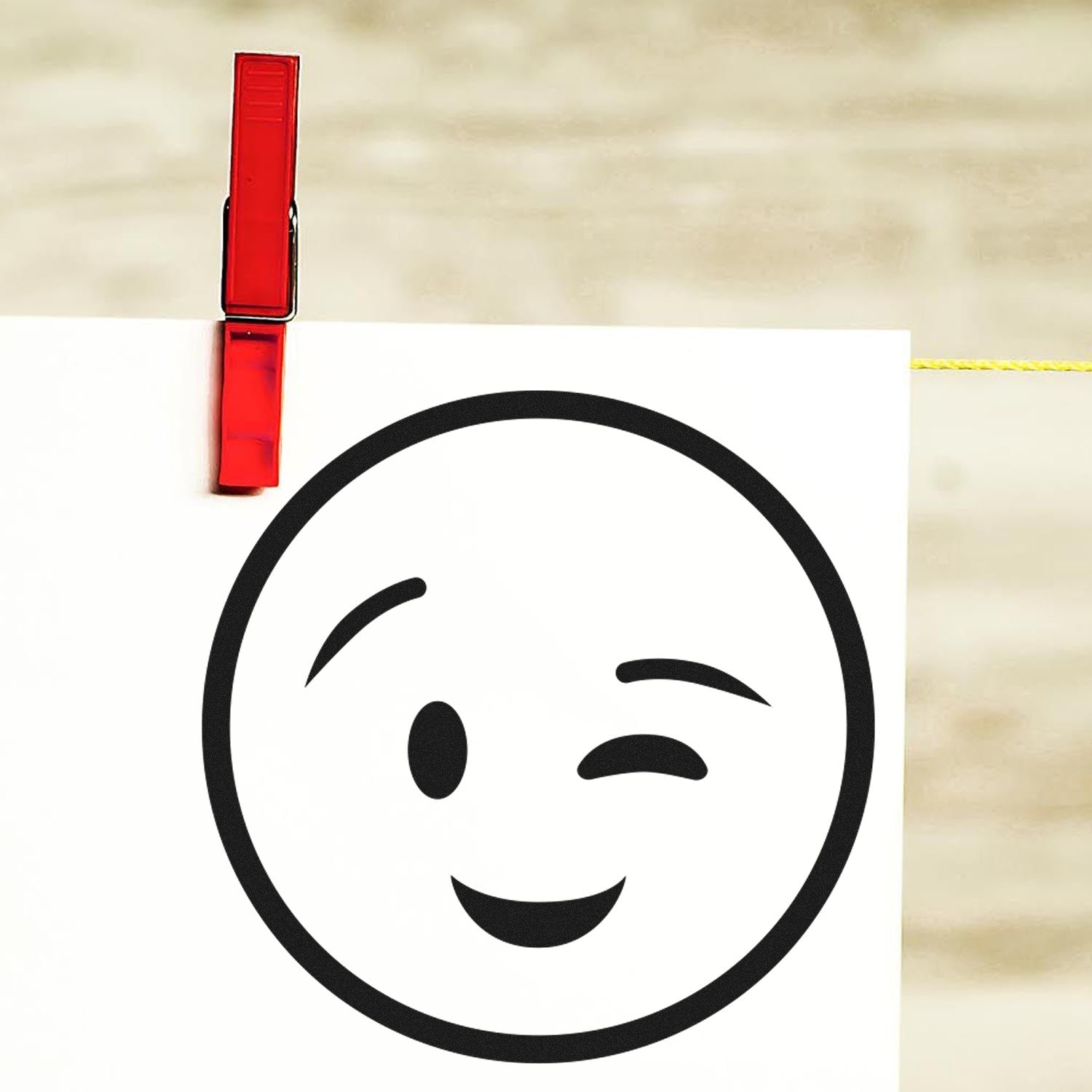 Self-Inking Winky Face Pictogram Stamp on paper, featuring a playful winking emoji design. Perfect for adding a fun touch to notes and crafts.