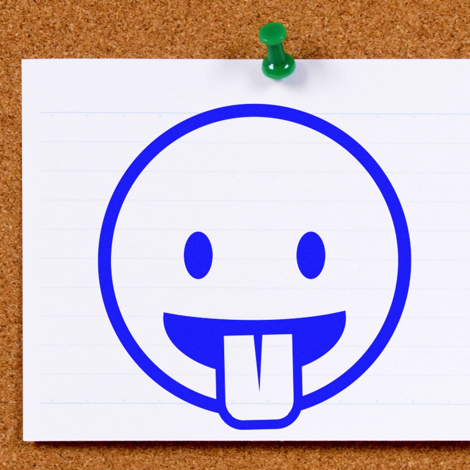 Wood Handle Goofy Grin Emoji Rubber Stamp on a corkboard, featuring a playful blue emoji with a tongue out on white paper. Perfect for adding fun to crafts and stationery.