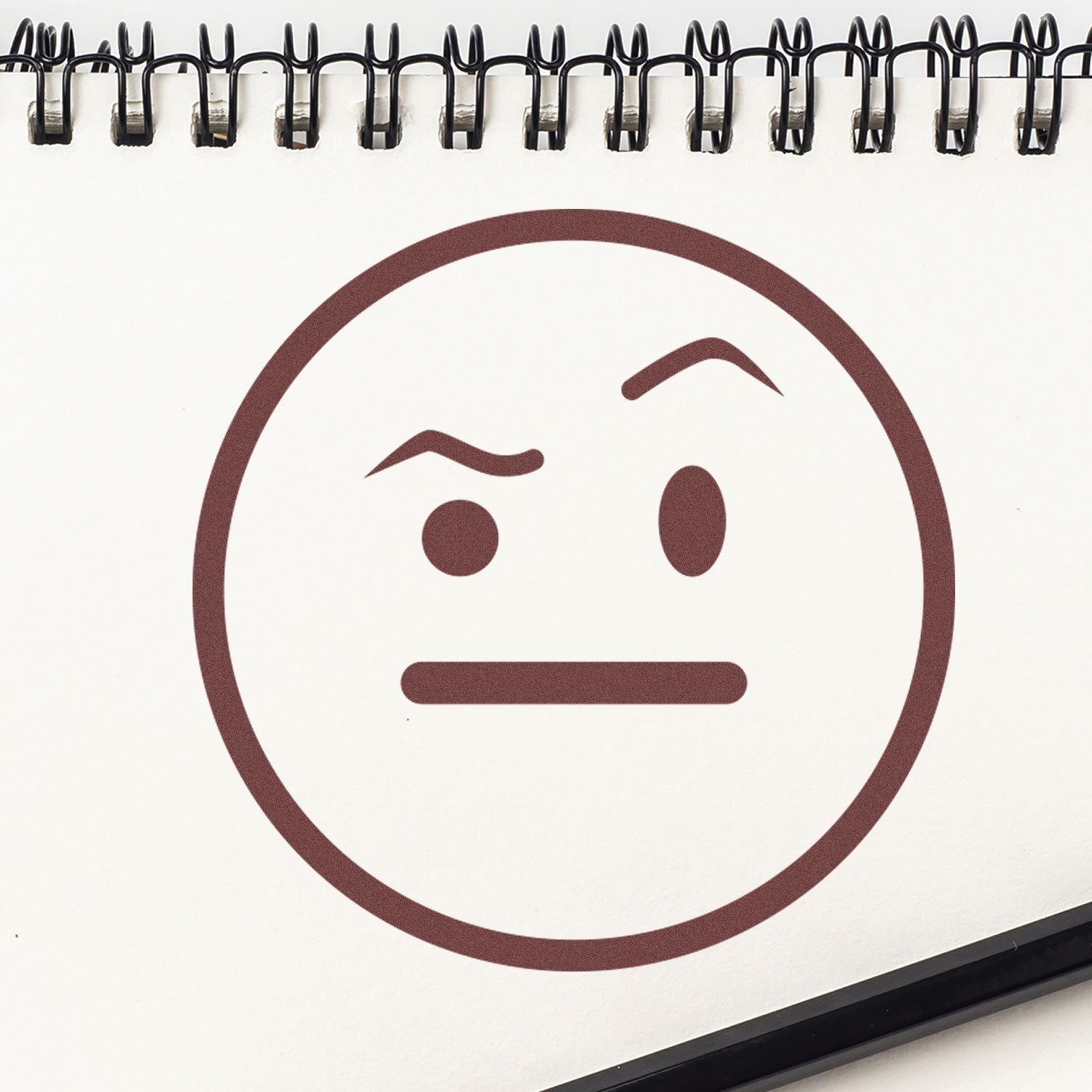 Image of a Self-Inking Skeptical Stare Emoji Stamp on a notepad, featuring a brown skeptical face with raised eyebrow and straight mouth, perfect for adding personality to documents and notes.