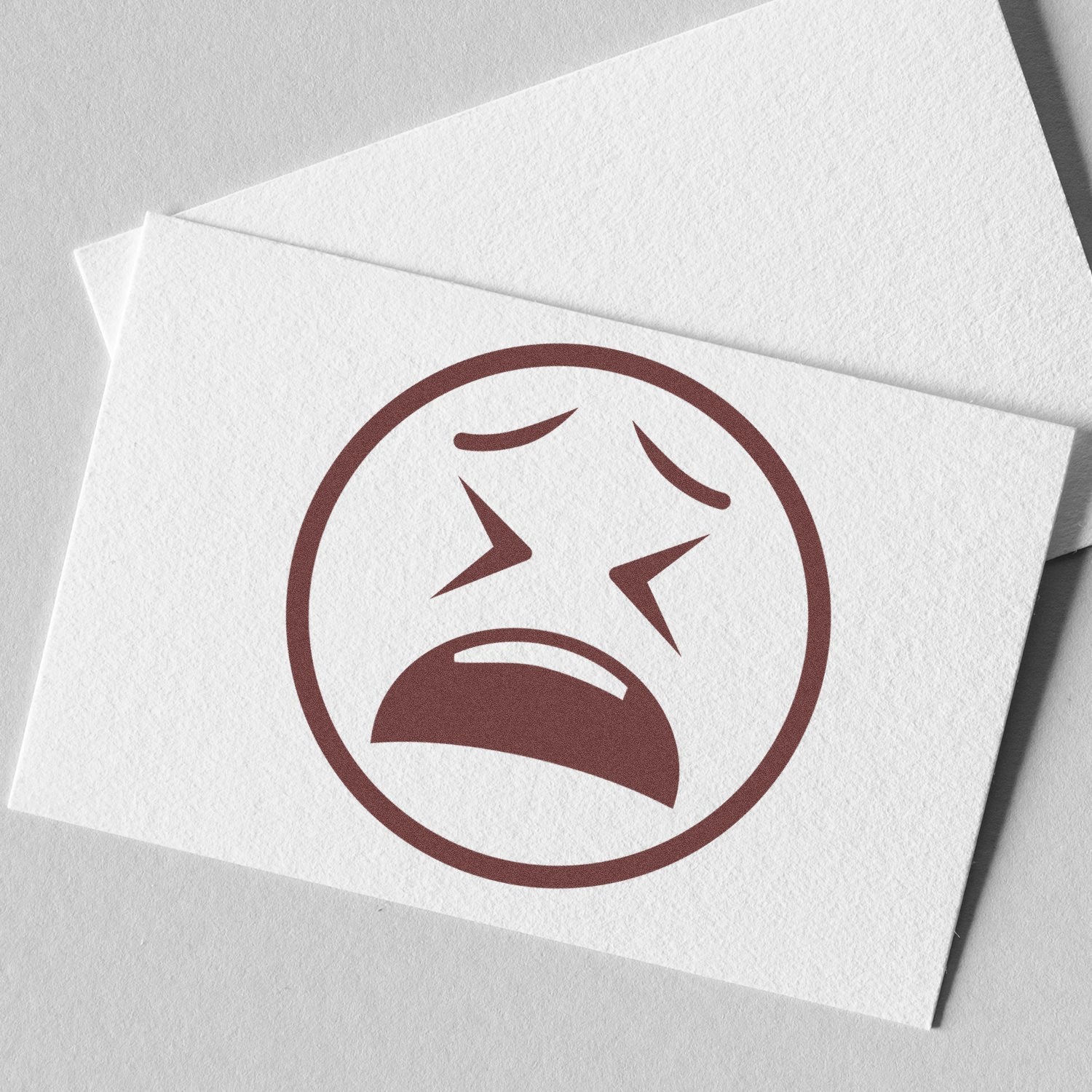 Self-Inking Clenched Cry Emoji Stamp on white paper, showcasing a brown crying face with clenched eyes and mouth. Perfect for adding expressive emotion to documents and crafts.